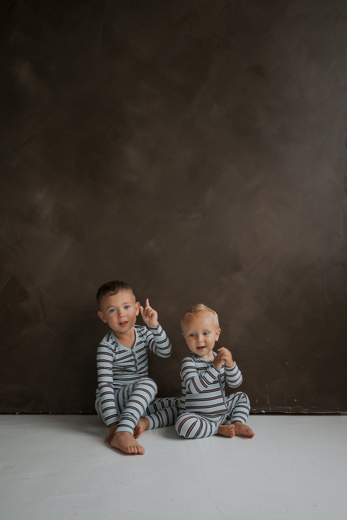 Two young children sit on the floor wearing light blue and brown striped ribbed Bamboo Two Piece Pajamas | Dean.