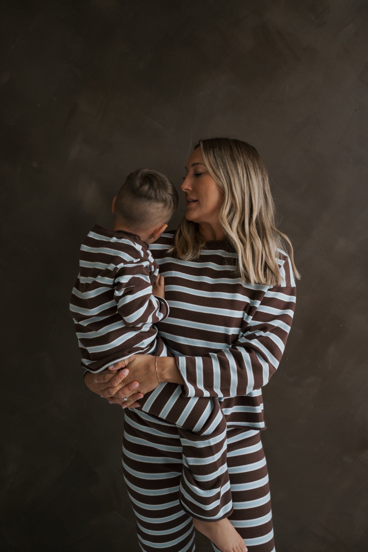 A woman and a young child wearing matching brown, white, and light blue striped oversized Women’s Knit Pant Set | Garrett *PRE-ORDER* knit sets.