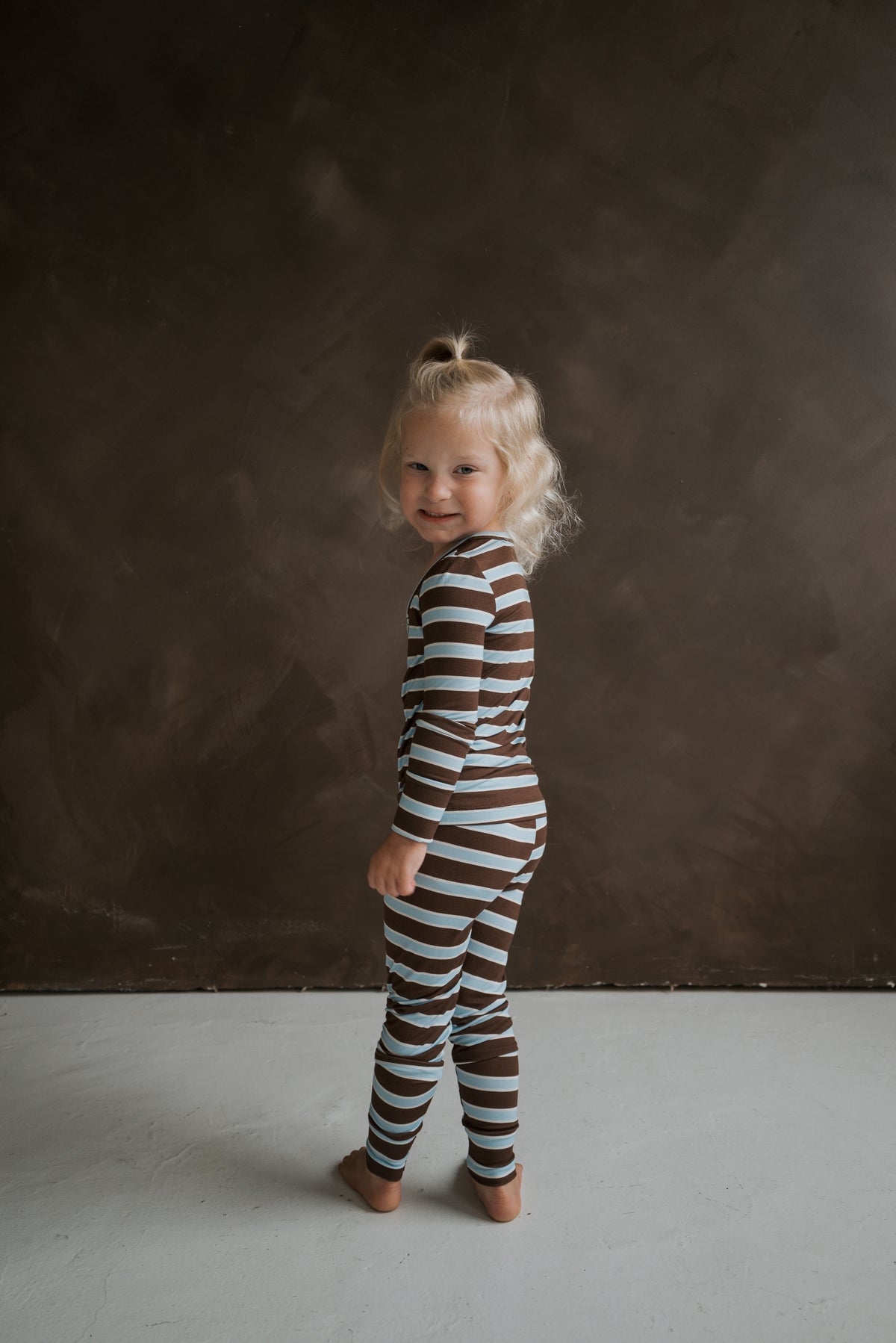 A young child wearing blue and brown horizontal striped Bamboo Two Piece Pajamas | Garrett.