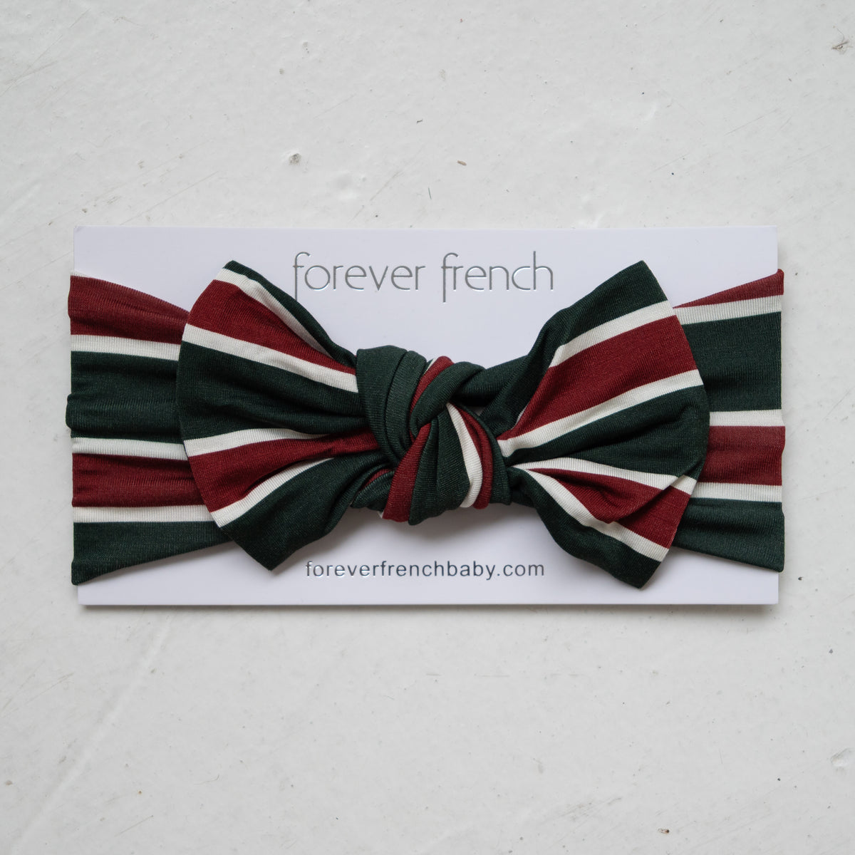 Forever French Baby Bamboo Head Wrap | Holiday Stripe featuring a knotted bow in a dark green, dark red, and white holiday stripe pattern.