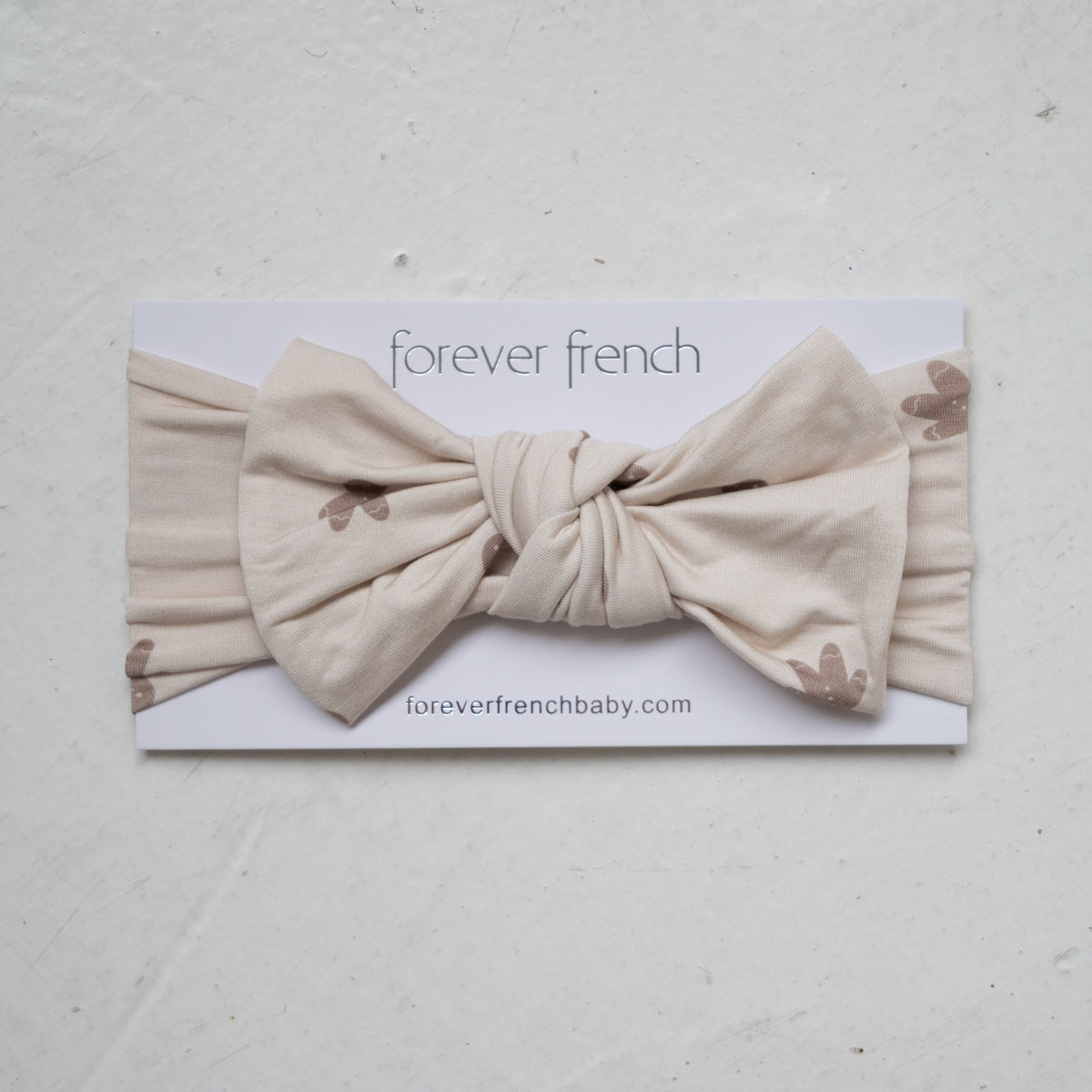 Forever French Baby Bamboo Head Wrap | Gingersnap in tan, featuring a knotted bow and a small brown gingerbread man print on this adjustable bamboo headwrap.