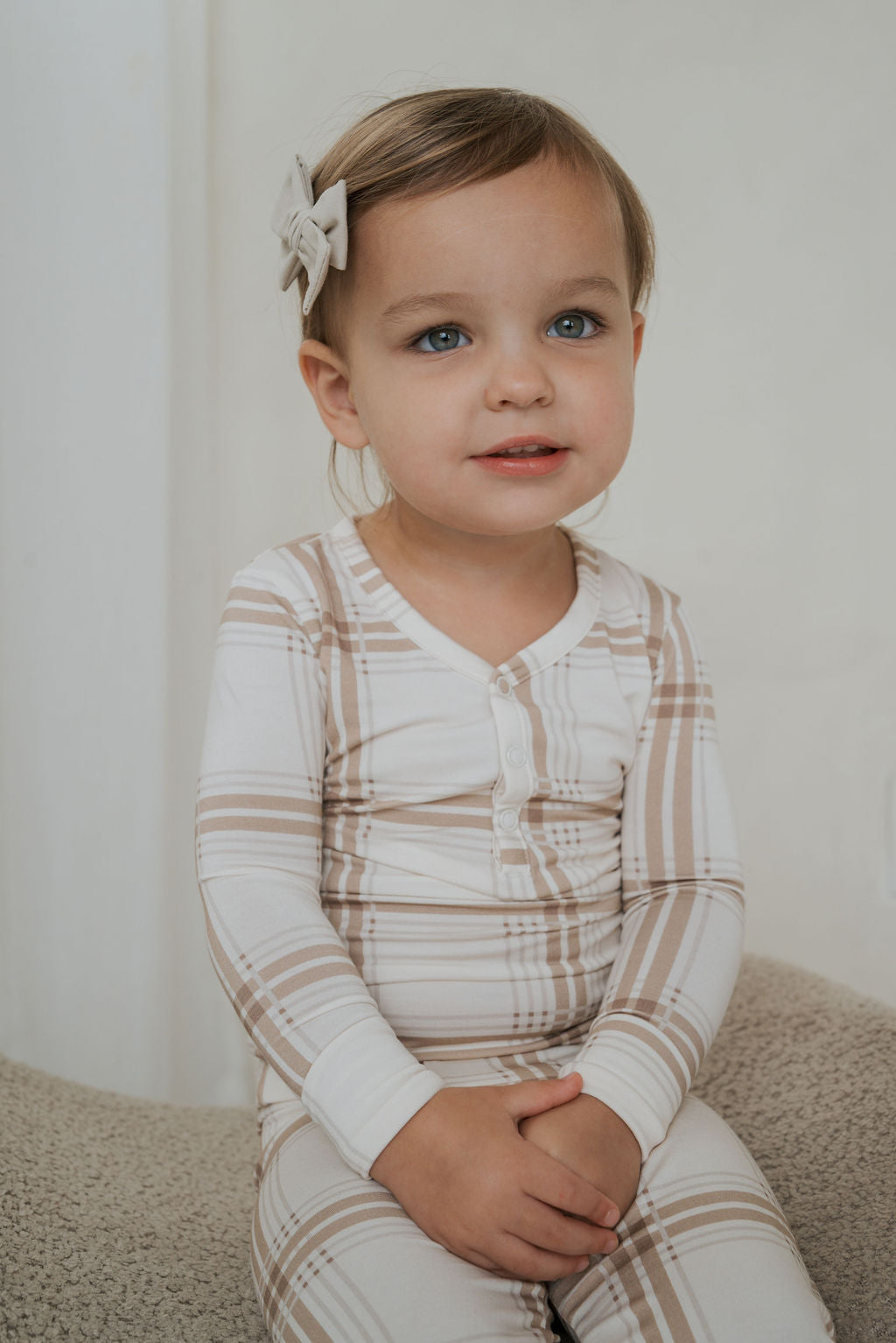 A toddler wearing a long-sleeved, beige and white plaid Bamboo Two Piece Pajamas | Ellis Plaid bamboo pajama set.
