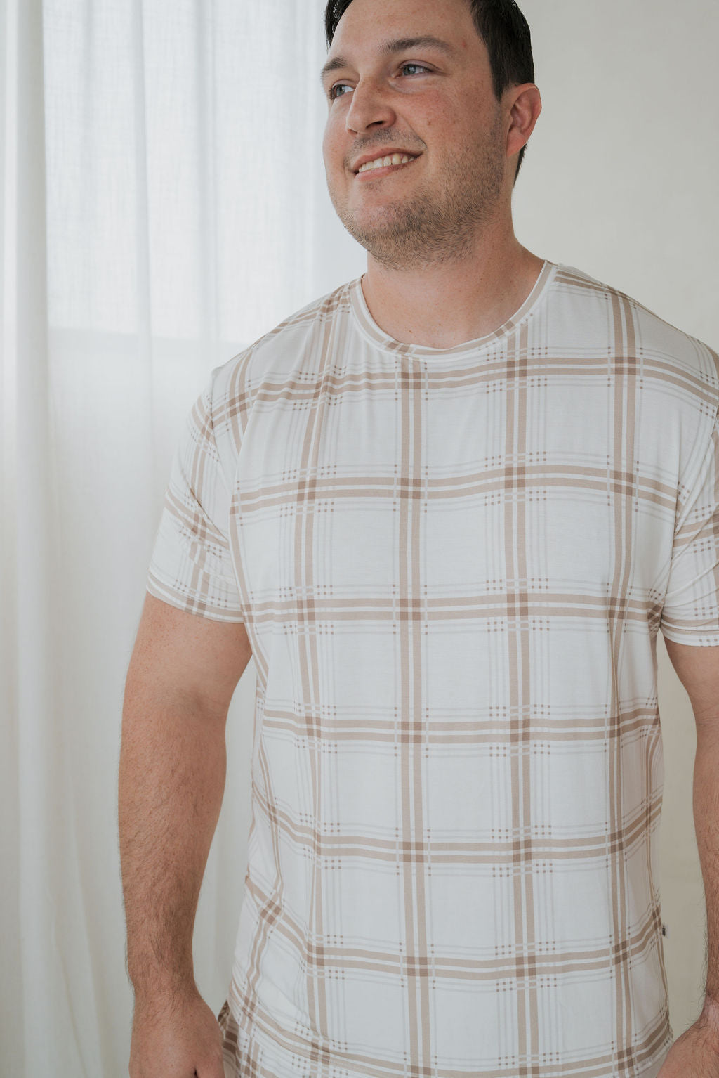 Man wearing a Men’s Short Sleeve Pajamas | Ellis Plaid set featuring a white short-sleeve shirt with a tan plaid pattern.
