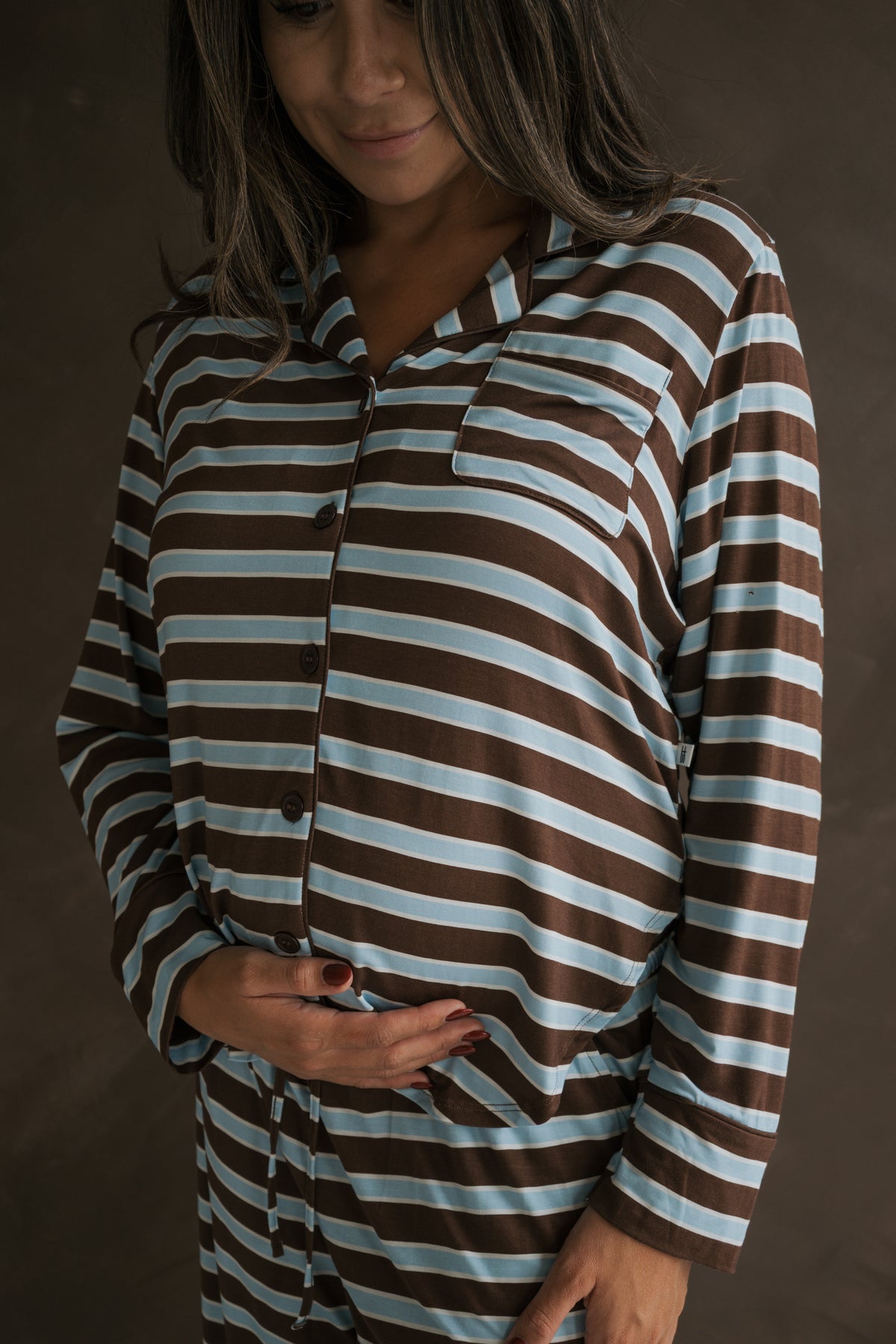 A person wears a Women’s Bamboo Button Up Lounge Set | Garrett in brown and light blue horizontal stripes, with one hand resting on their midsection.