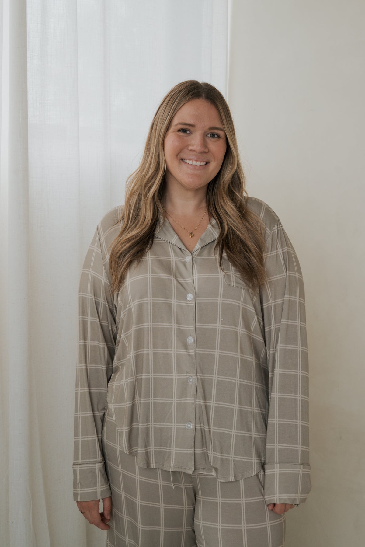 A woman wearing a Women’s Bamboo Button Up Lounge Set in Linen Grid, featuring a tan button-up shirt with a white grid pattern and matching wide-leg pants.
