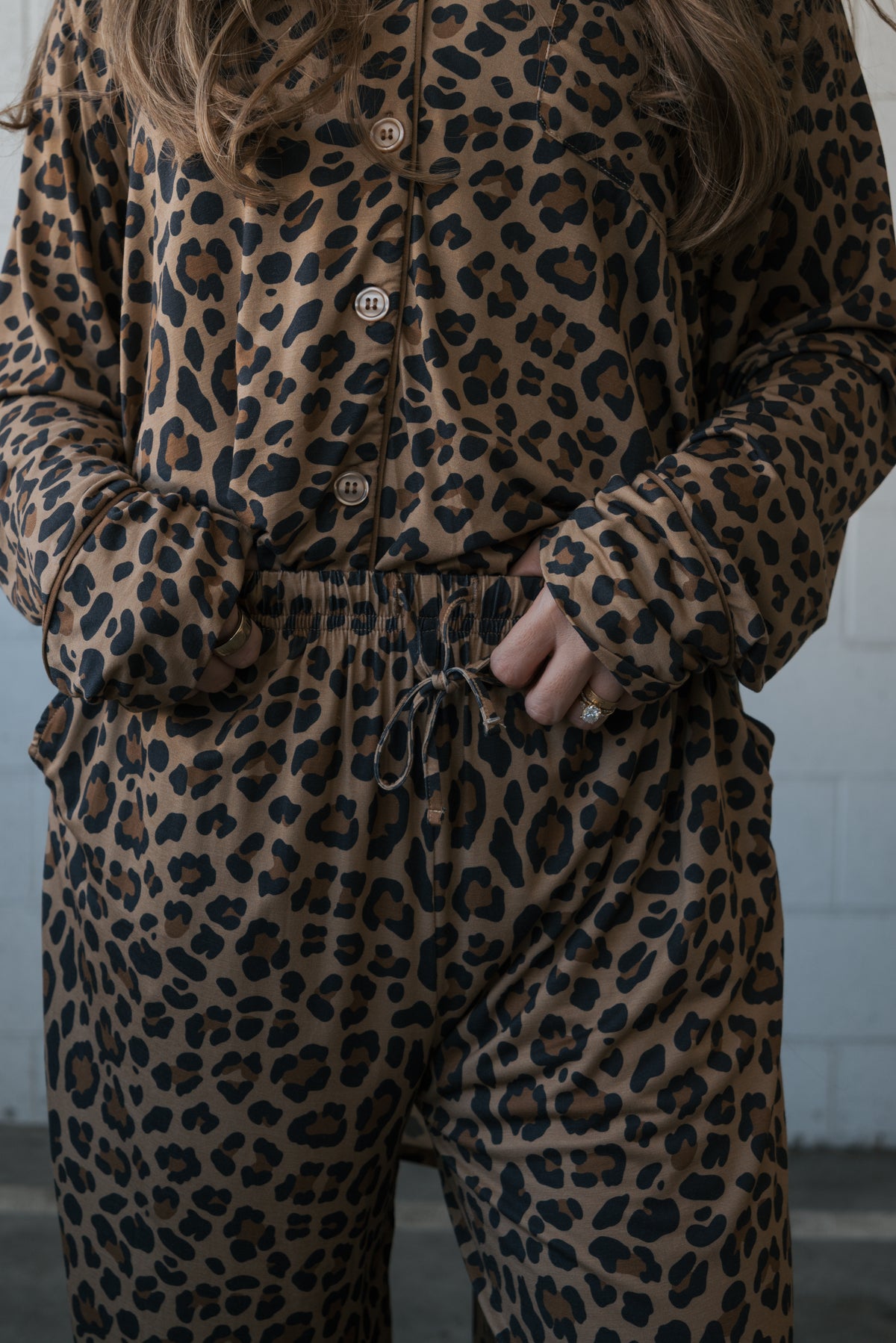 A person wearing a Women’s Bamboo Button Up Lounge Set | Leopard consisting of a long-sleeved button-up shirt and drawstring pants with pockets.