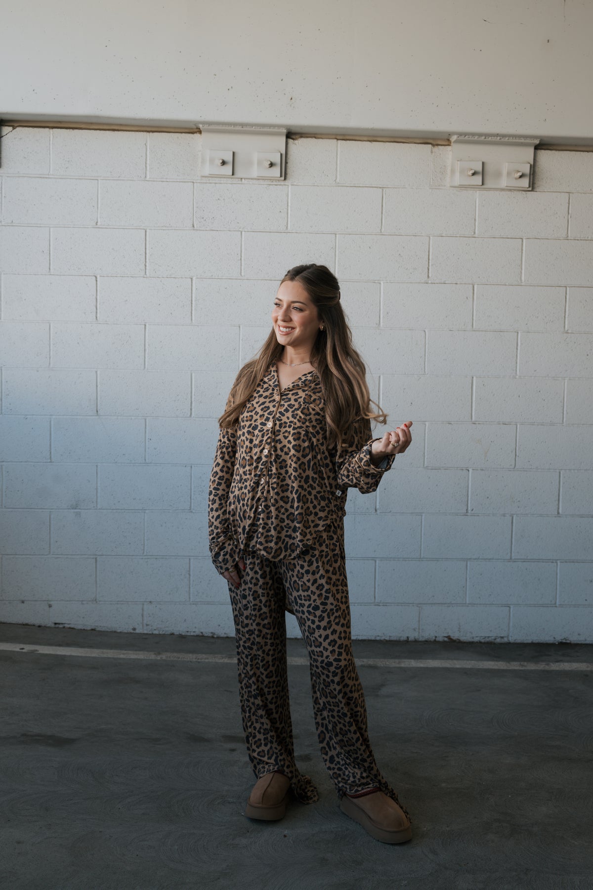 A woman wearing a Women’s Bamboo Button Up Lounge Set | Leopard, featuring a long-sleeved button-up shirt and matching wide-leg pants in a leopard print.