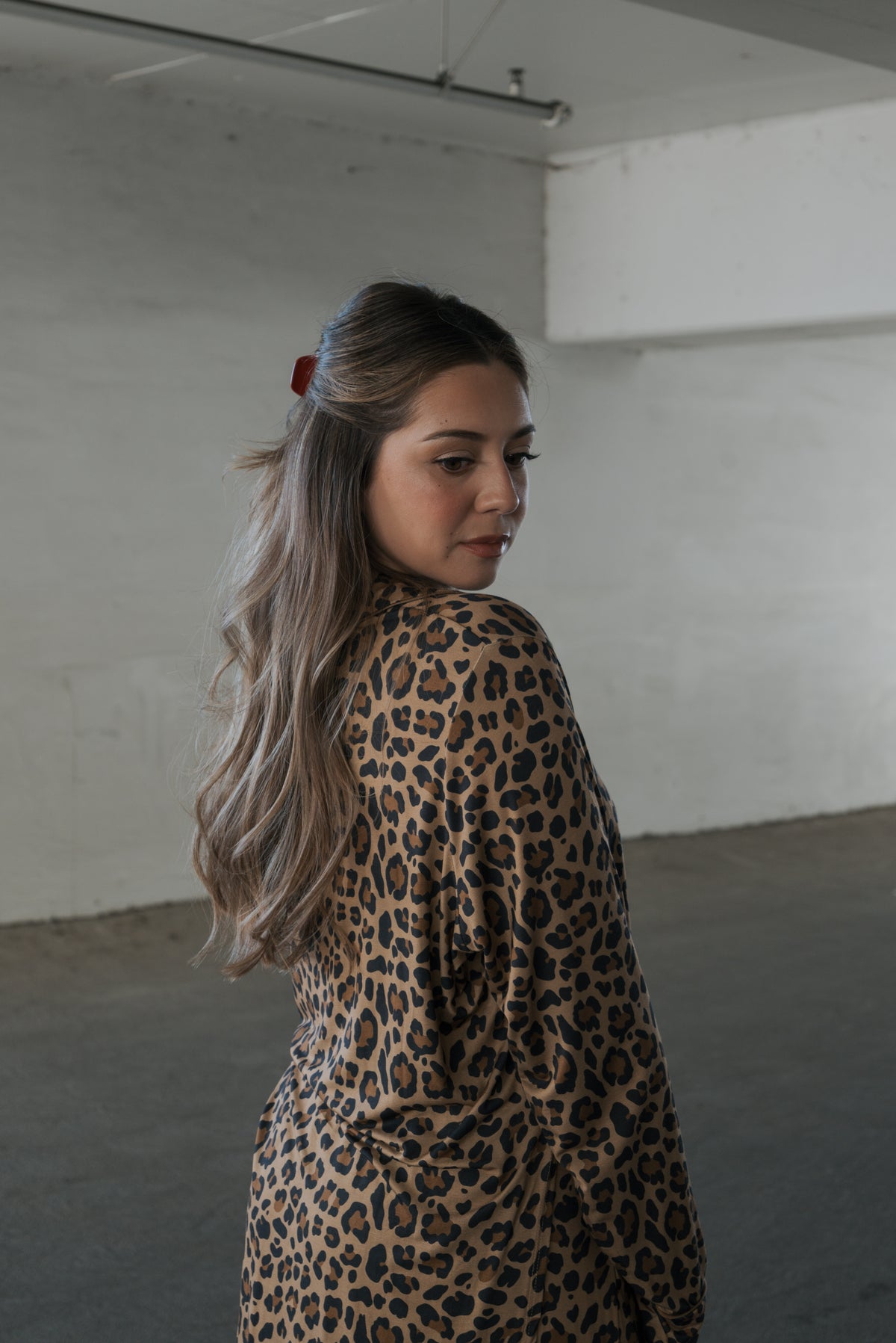 A woman wearing a Women’s Bamboo Button Up Lounge Set in leopard print looks over her shoulder.