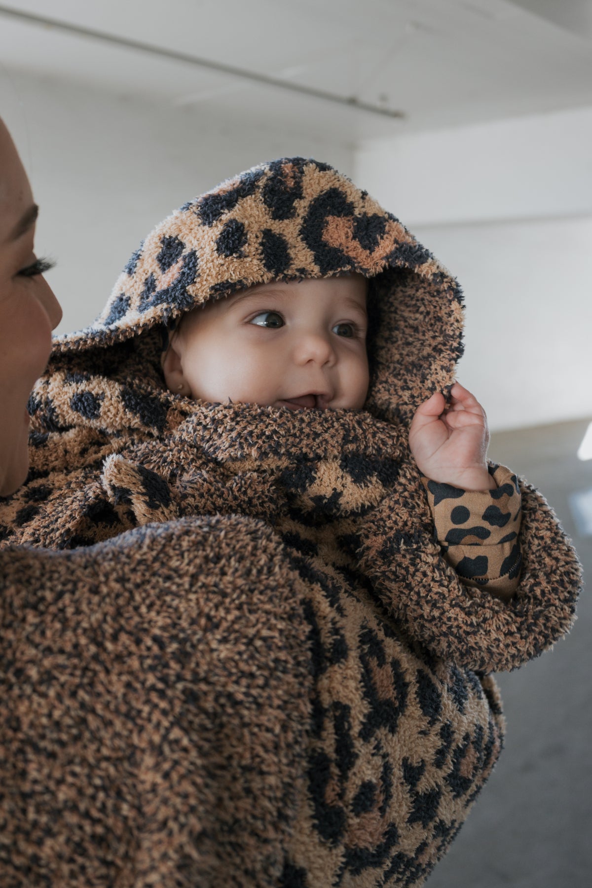 An adult holds a baby wrapped in a soft, leopard-print Children’s Robe | Leopard by forever french baby.