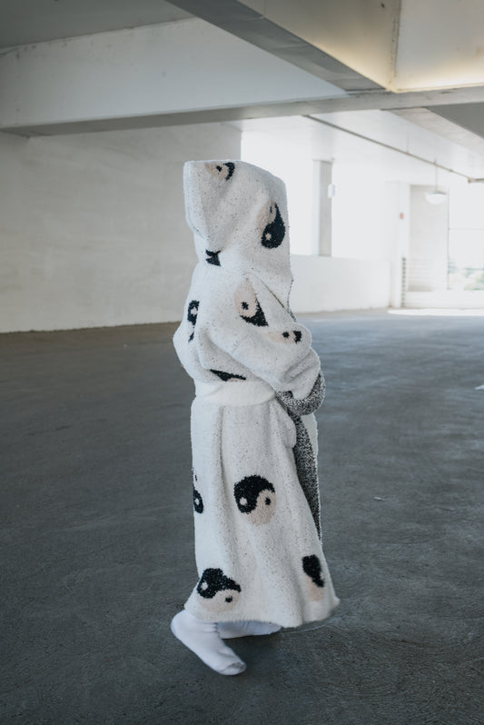 Child wearing a Children’s Robe | Yin Yang, a microfiber feather yarn hooded robe patterned with black and tan yin yang symbols.