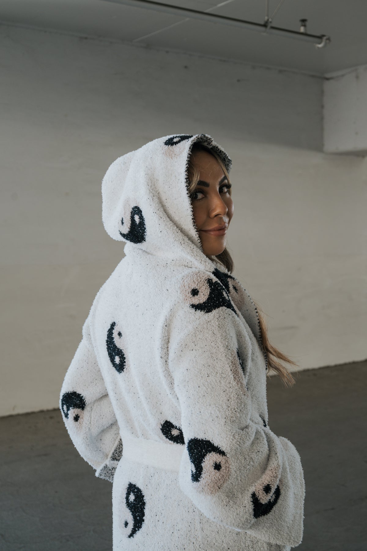 A person wearing a white and black Adult Robe | Yin Yang by forever french baby looks over their shoulder.