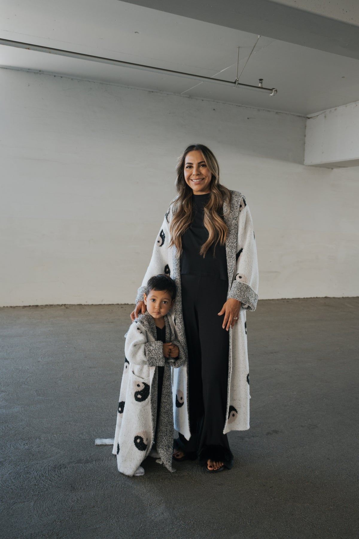 A woman and a young child stand side-by-side in matching, Oeko-tex certified Children’s Robe | Yin Yang white robes patterned with black yin-yang symbols.