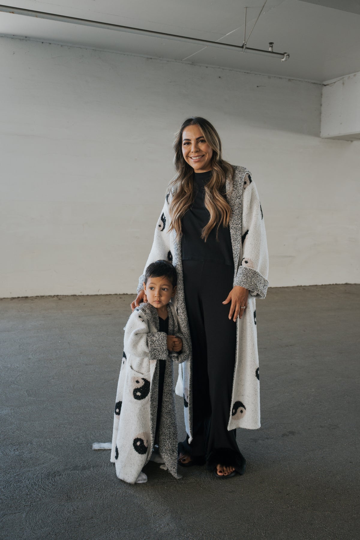 An adult wearing an Adult Robe | Yin Yang and a young child stand side-by-side in matching white robes patterned with black yin-yang symbols.
