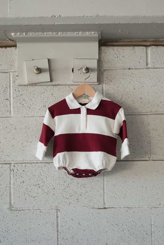 Forever French Baby Rugby Sweatshirt Romper in Deep Cranberry, a long-sleeved baby romper with wide cranberry and white horizontal stripes, a polo collar, and bottom snaps.