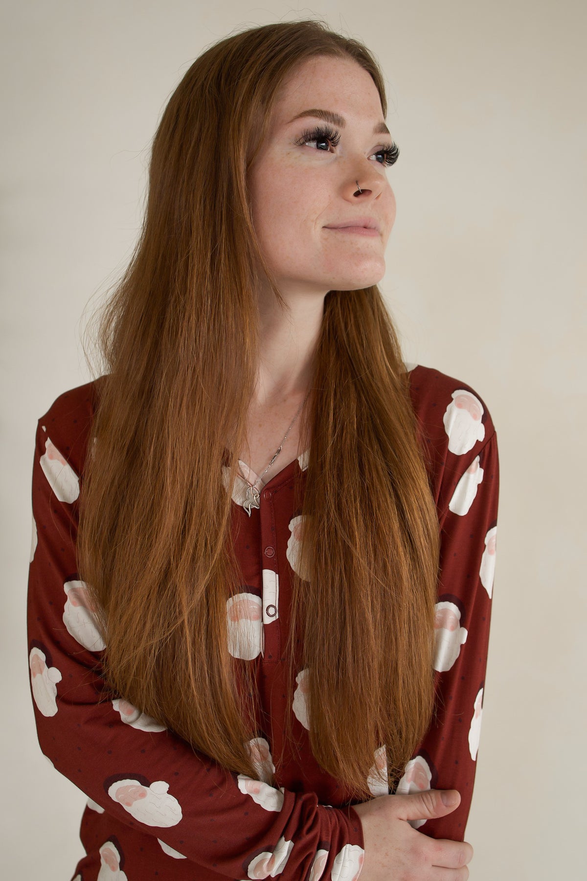A person wearing a maroon Women’s Long Sleeve Bamboo Pajama | Vintage Santa patterned with vintage-style Santa Claus faces.