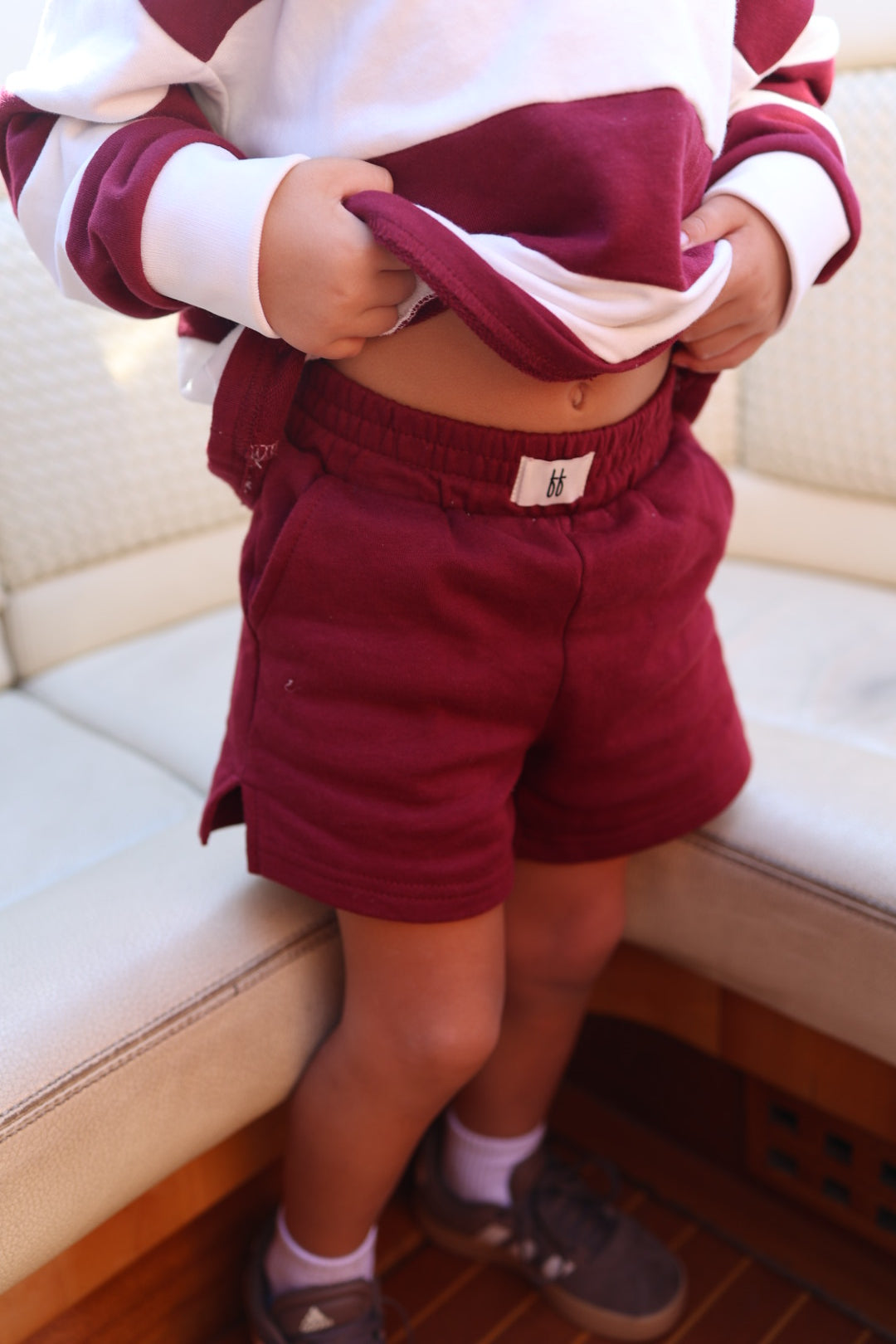 A toddler wearing deep cranberry Child Terry Shorts by forever french baby, featuring an elastic waistband.