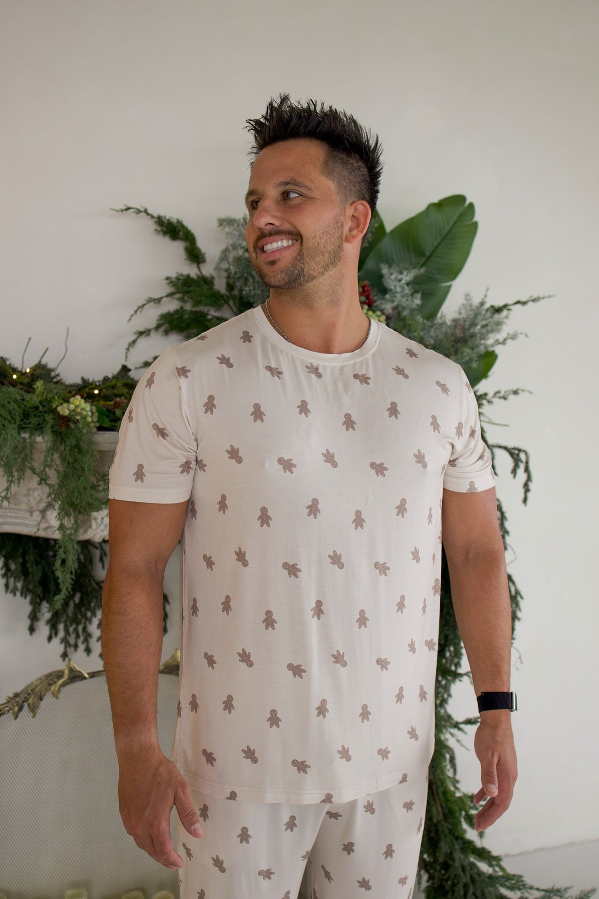 A man wearing a Men’s Short Sleeve Pajamas | Gingersnap set featuring a repeating gingerbread man pattern.