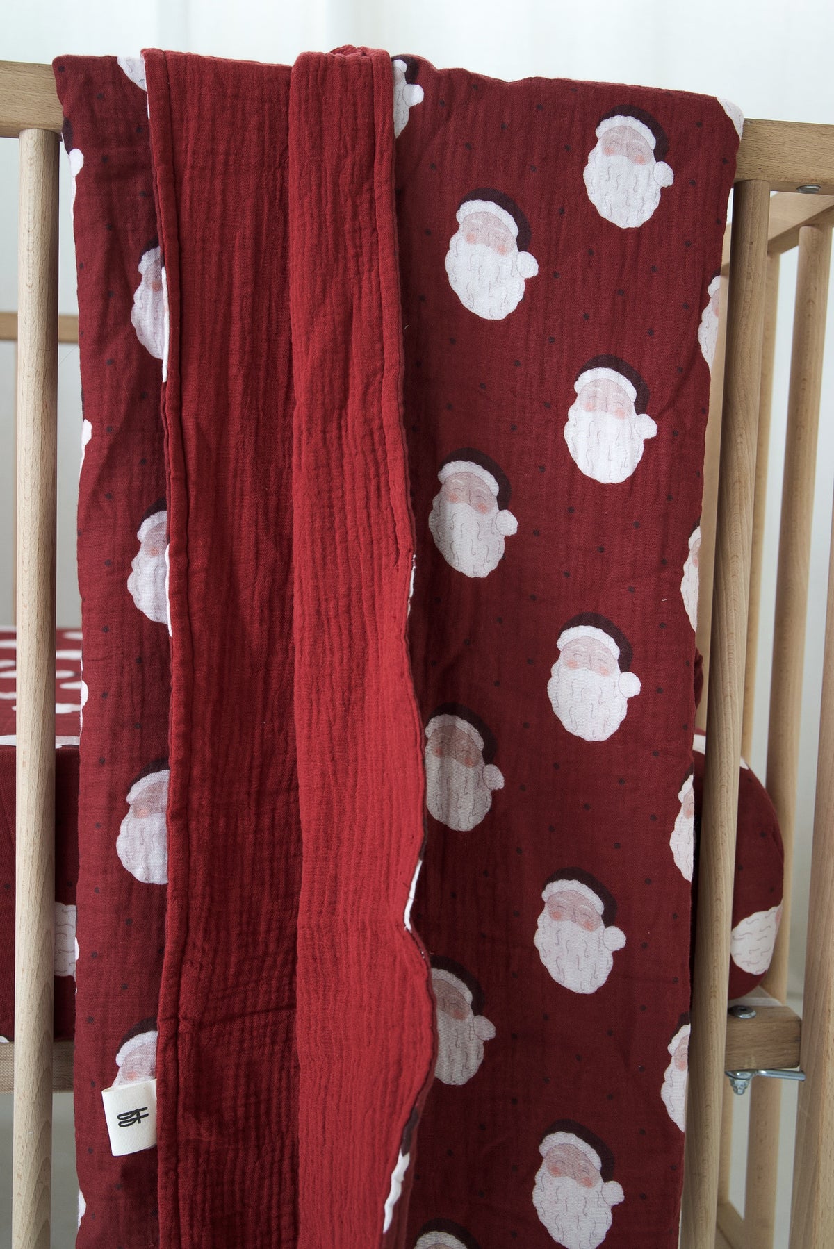 Dark red forever french baby Muslin Quilt | Vintage Santa draped over a wooden crib.