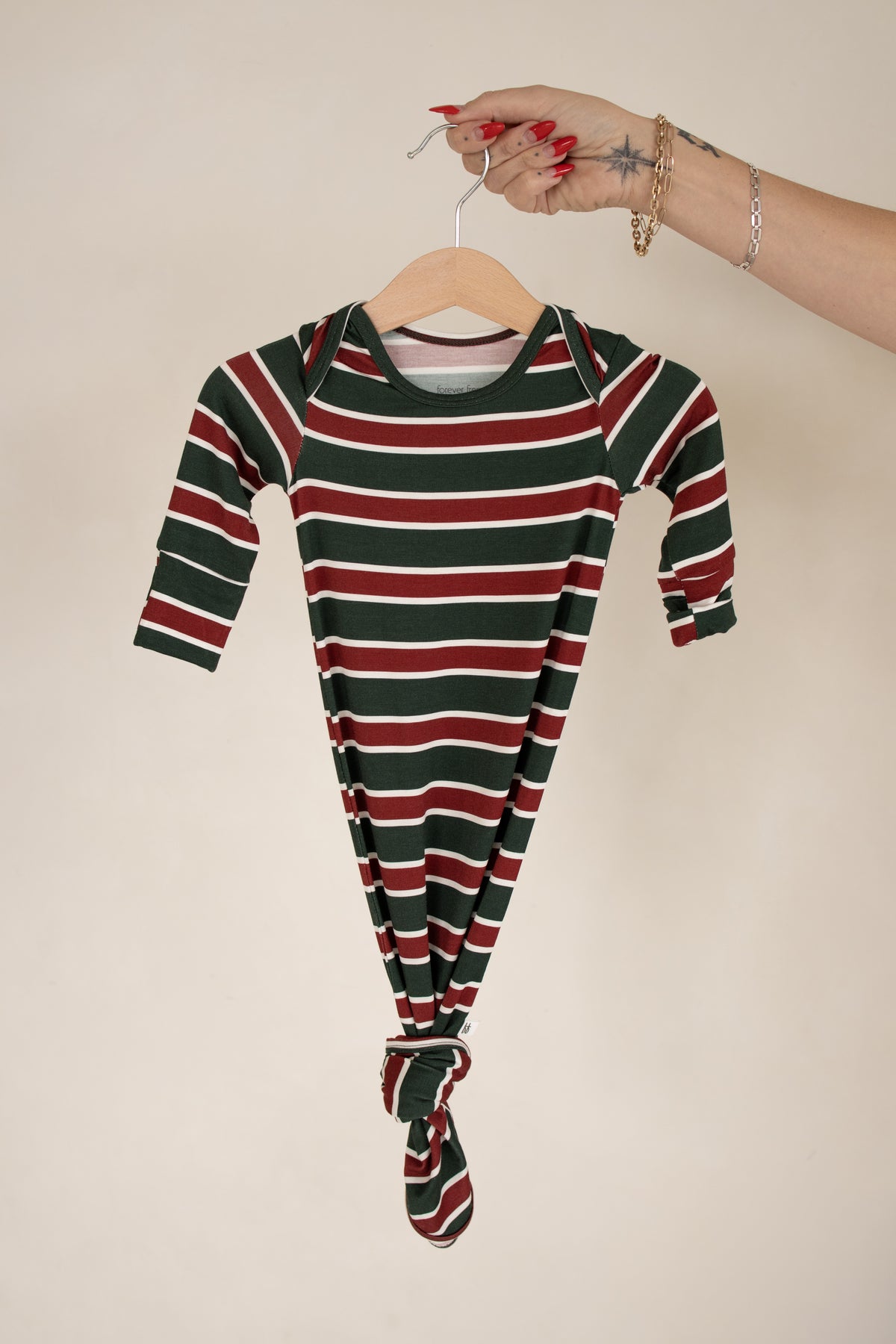 Forever French Baby Bamboo Knotted Gown | Holiday Stripe, a long-sleeved newborn gown with a knotted hem in a red, green, and white horizontal stripe pattern.