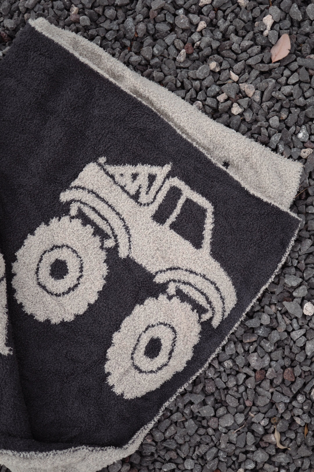The forever french baby Plush Blanket | Monster Truck, featuring a bold design, is displayed on gray gravel stones.