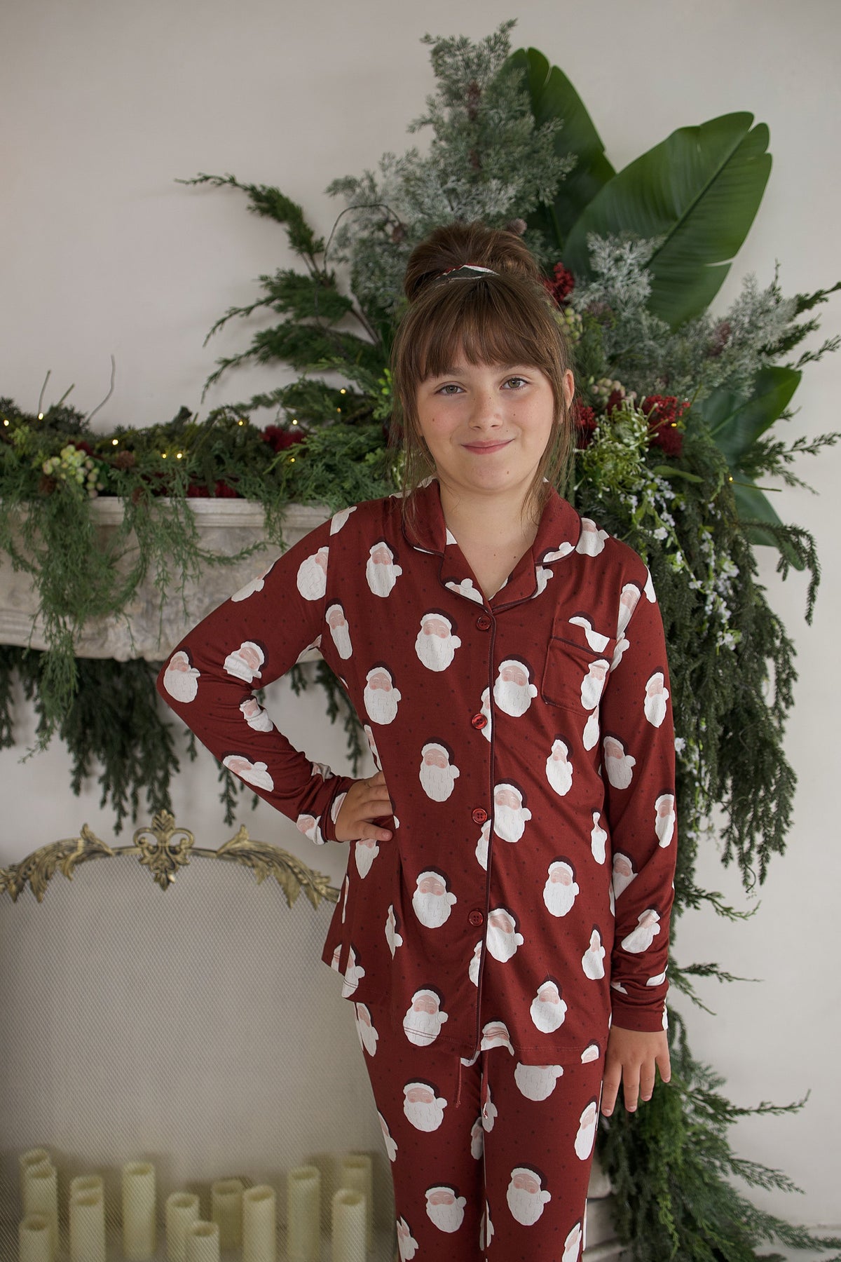 A young girl wearing the Girl’s Bamboo Button Up Lounge Set | Vintage Santa by forever french baby, featuring a vintage Santa Claus print.