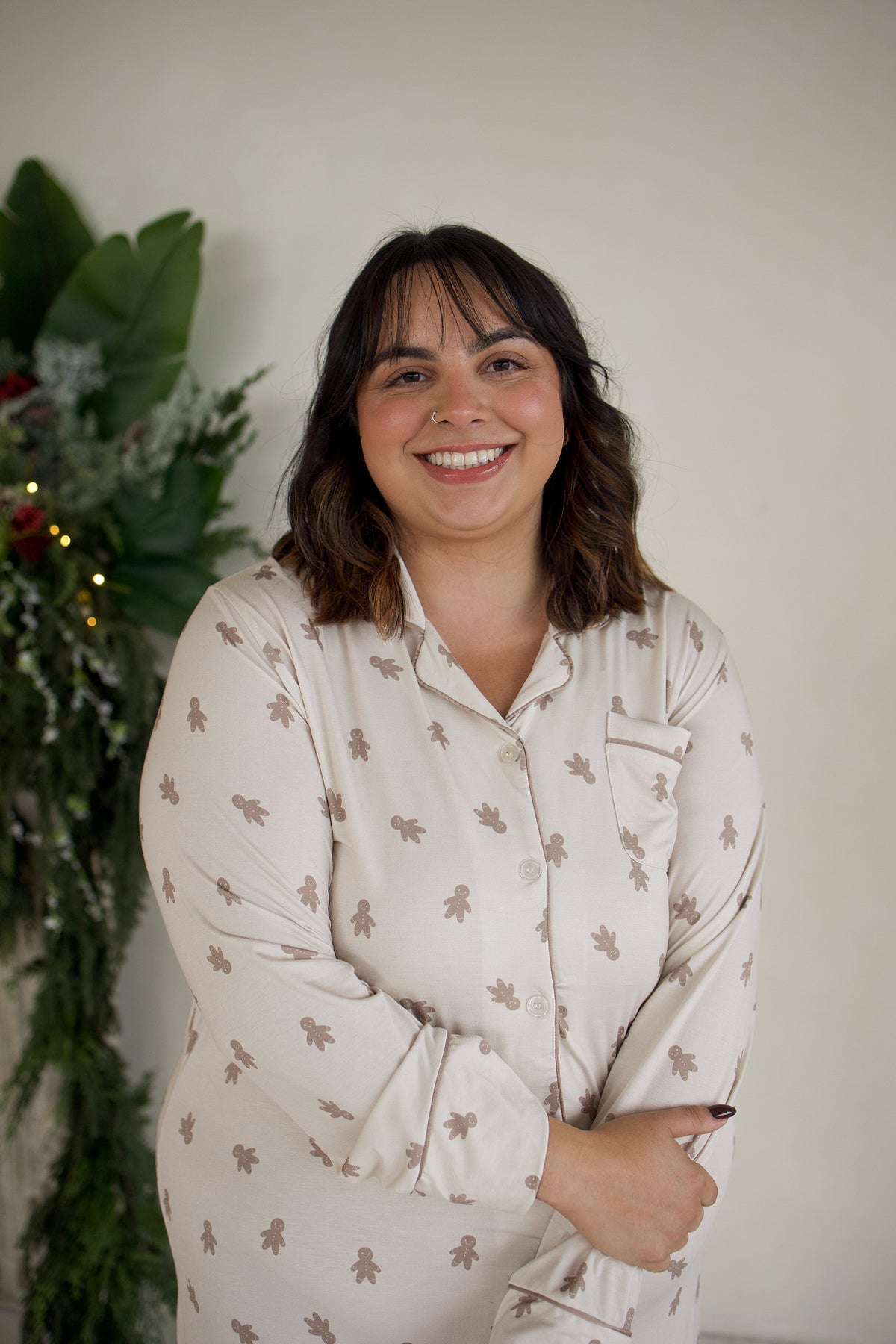 A smiling woman wearing a Women’s Bamboo Sleeping Dress | Gingersnap in a light color with a brown gingerbread man print.