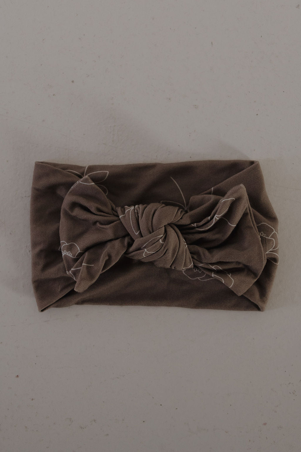 The Bamboo Head Wrap | Sweet Dreams Floral from forever french baby, featuring a large twisted bow, is displayed flat on a light gray surface.