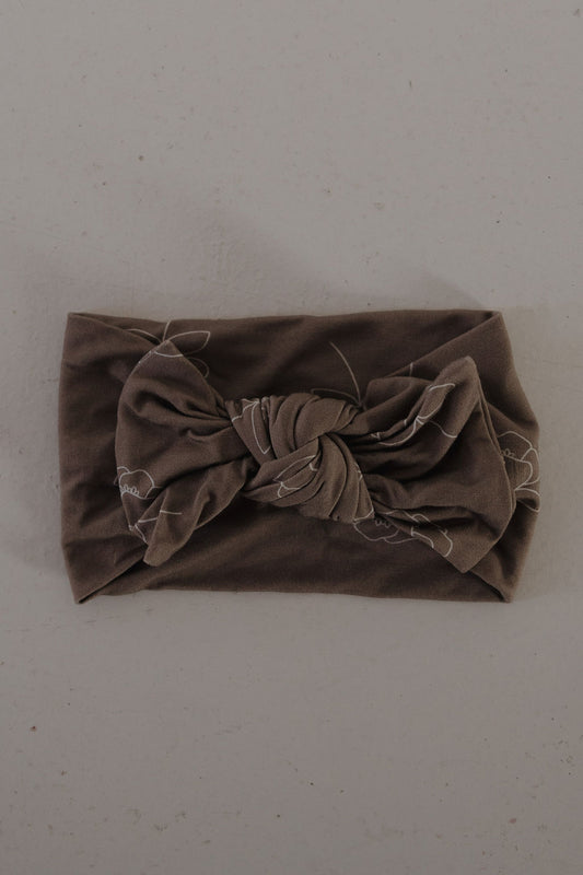 The Bamboo Head Wrap | Sweet Dreams Floral from forever french baby, featuring a large twisted bow, is displayed flat on a light gray surface.