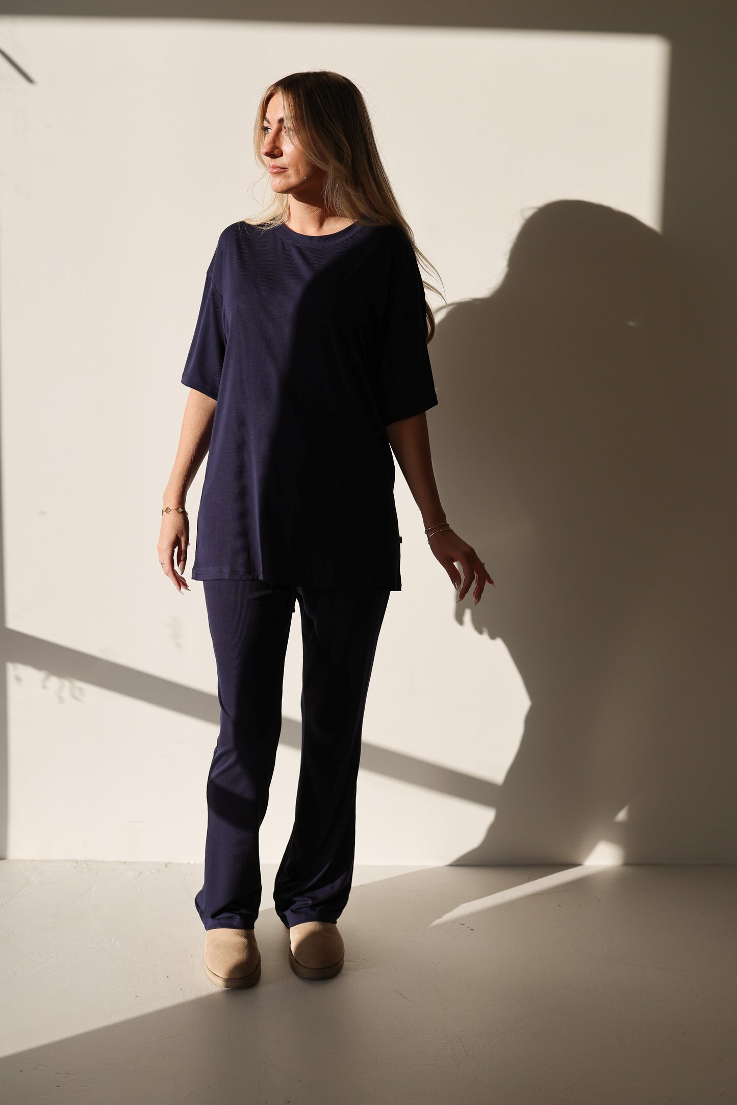 A woman stands in a room, comfortably dressed in the forever french baby Short Sleeve Bamboo Women's Lounge Set in Blueberry Ribbed.