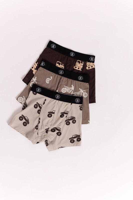 The forever french baby Bamboo Boxers (3 Pack) feature dirt bike, bulldozer, and monster truck prints in brown, tan, and beige with black waistbands—hypoallergenic bamboo underwear designed for kids.