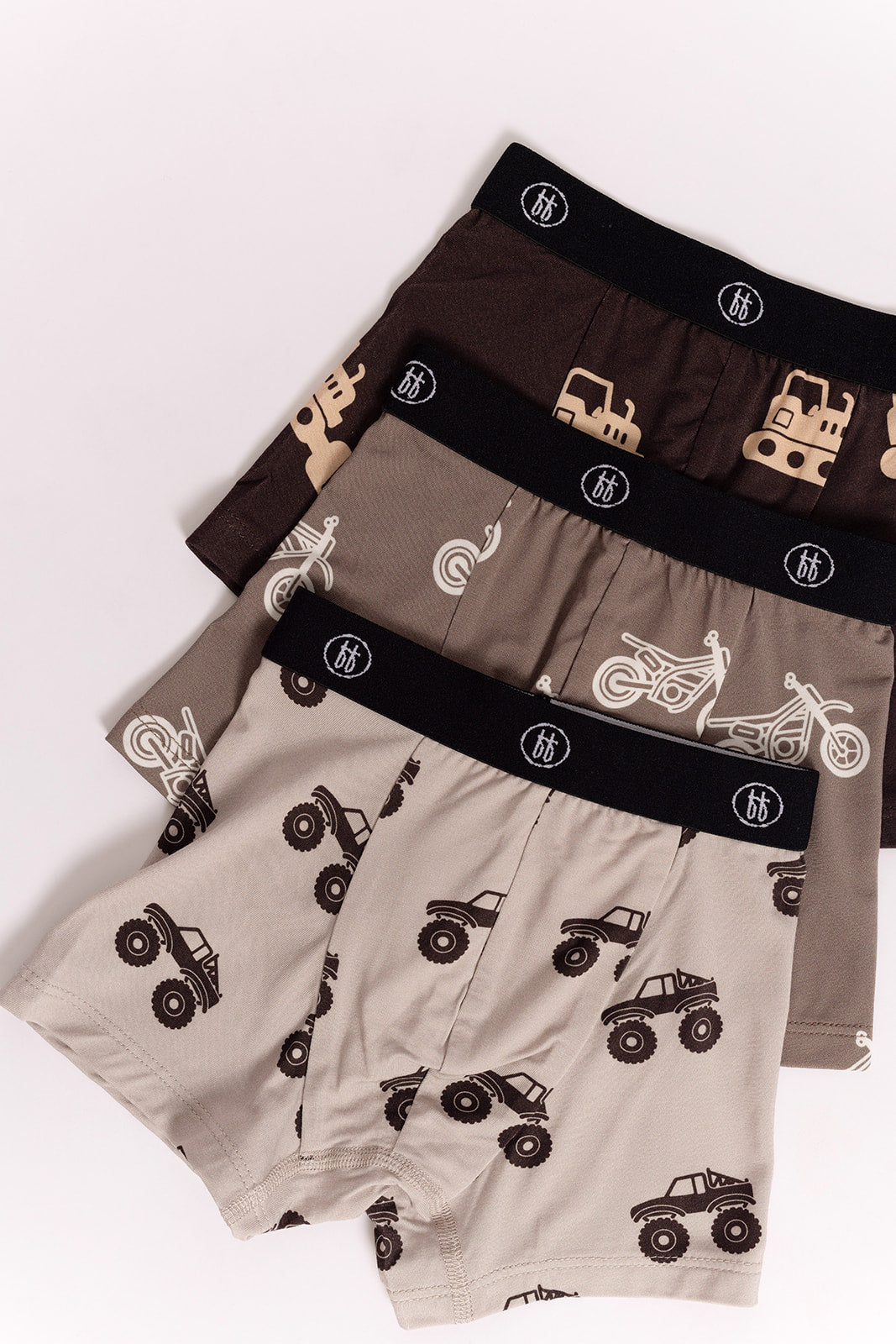 A 3-pack of forever french baby Bamboo Boxers, featuring dirt bike, bulldozer, and monster truck prints in brown and beige tones, are stacked neatly on a white background.