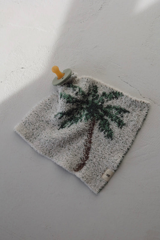 The forever french baby Lovey | Palm Tree features a yellow pacifier attached to a soft, square security blanket with a palm tree design, shown on a light textured surface.