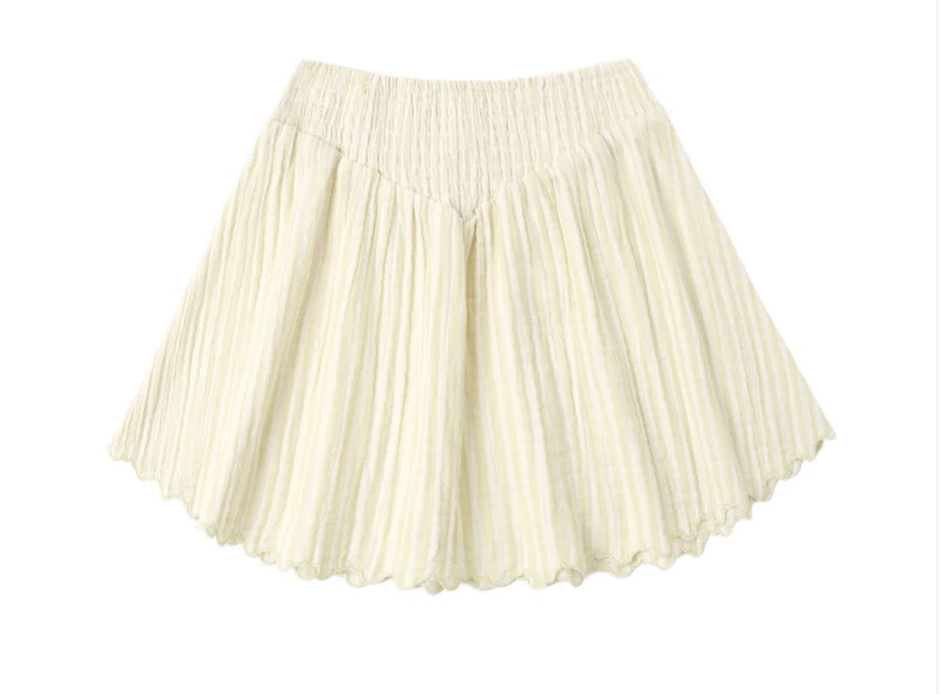 The Smocked V Mini Skirt | Citron Stripe by Rylee + Cru is crafted from 100% cotton in a subtle citron stripe pattern and features pleated detailing, a wide elastic waistband, and a slightly flared hem. Displayed on a white background, this cream-colored skirt combines smocked accents with an easy, comfortable fit.