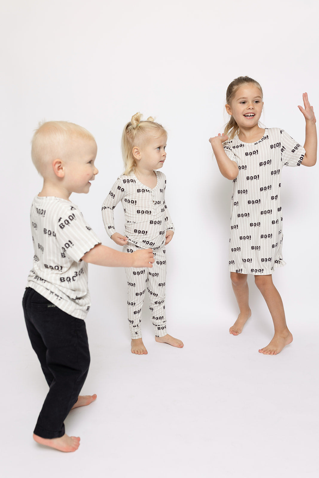 Three young children smile and play together in matching forever french baby Bamboo Two Piece Pajamas | Boo! outfits. Their joy shines in these breathable pajamas, perfect for active play and comfort.