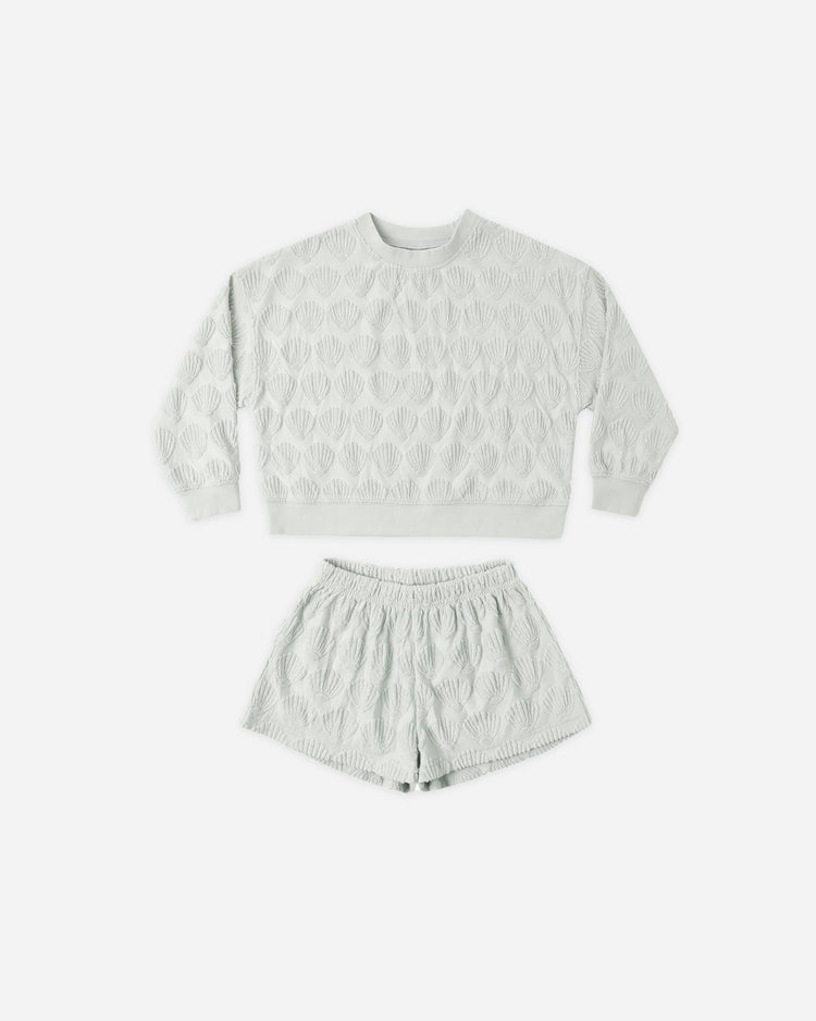 The Karli Set by Rylee + Cru, shown on a plain white background, features a light gray terry cloth sweatshirt and matching shorts with a raised shell pattern that evokes a relaxed coastal vibe.