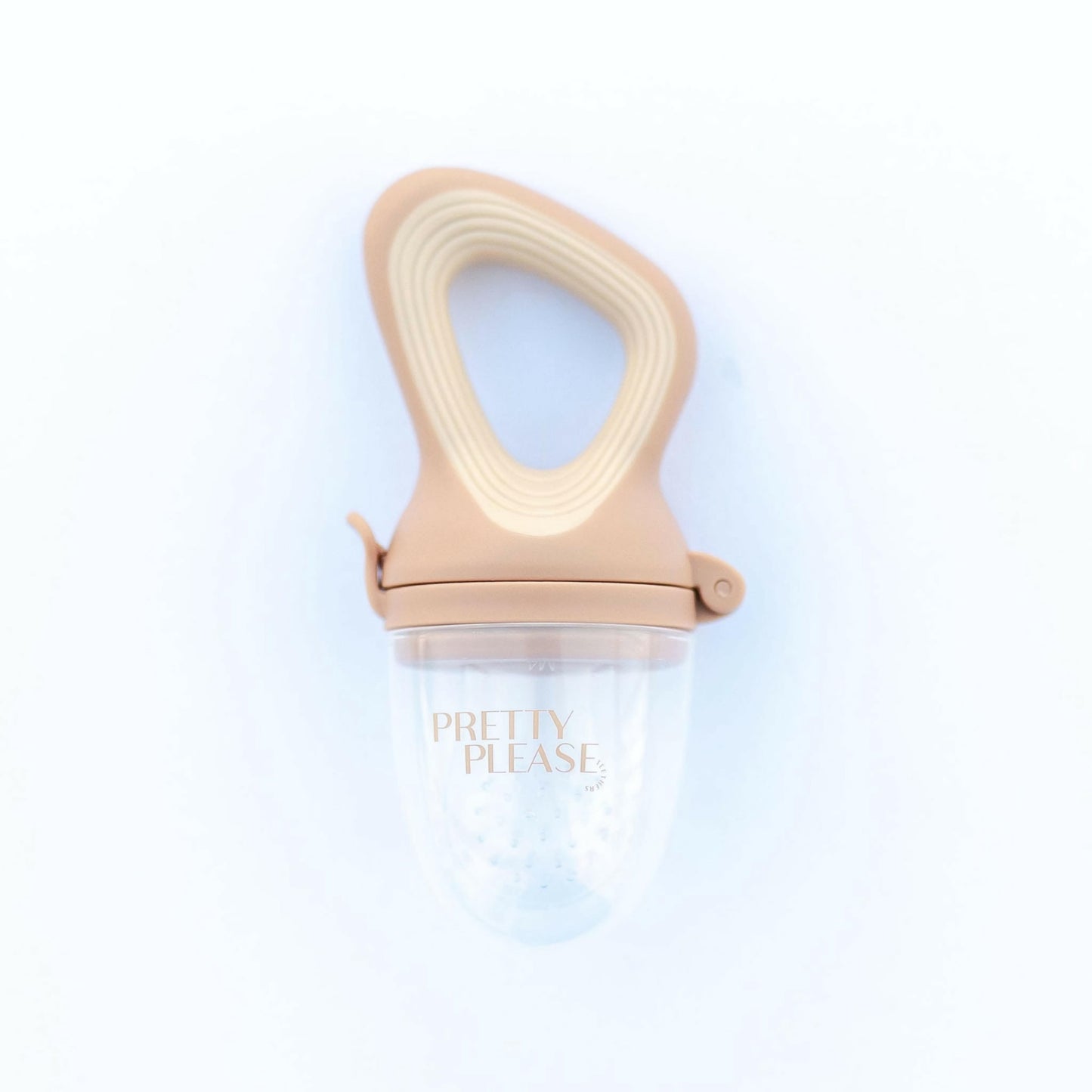 The Modern Mod Feeder by forever french baby is a beige, semi-transparent baby food feeder featuring a handle and silicone mesh, perfect for introducing solid foods to infants. "Pretty Please" is printed on the front of this eco-friendly teether, which is designed with care. The background is white.