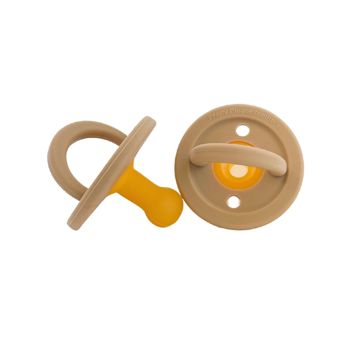 Two Modern Pacifier | Oat pacifiers by forever french baby are shown. One is lying flat with the nipple to the left, while the other is standing on its base. Both have circular shields with handles, exemplifying baby essentials. The yellow nipple adds a pop of color to these silicone teethers.