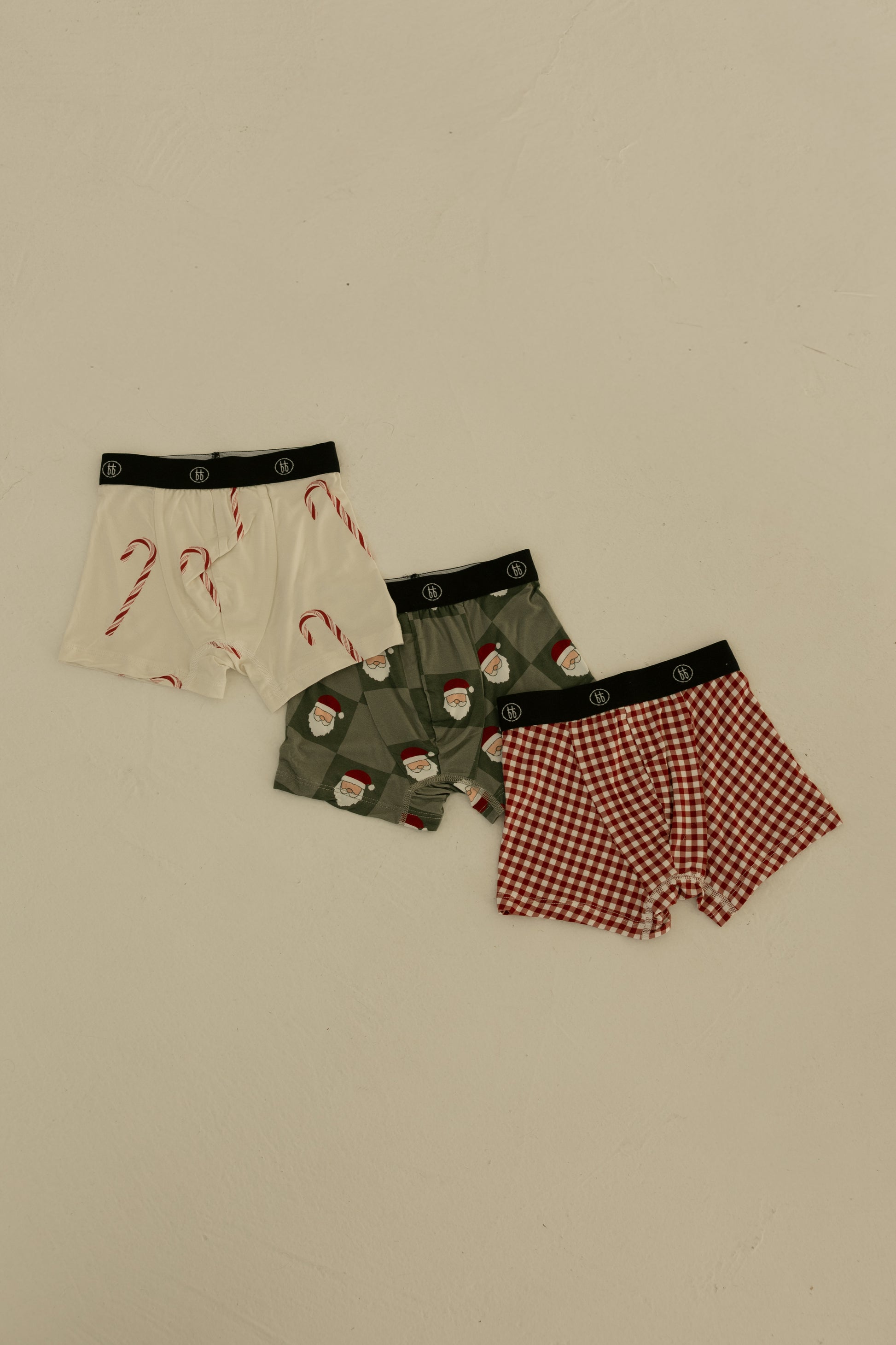 The forever french baby Bamboo Boxers (3 Pack) features red gingham, candy cane, and Santa checkerboard prints—soft, hypoallergenic boys' underwear with black waistbands, ideal for kids and shown on a neutral background.