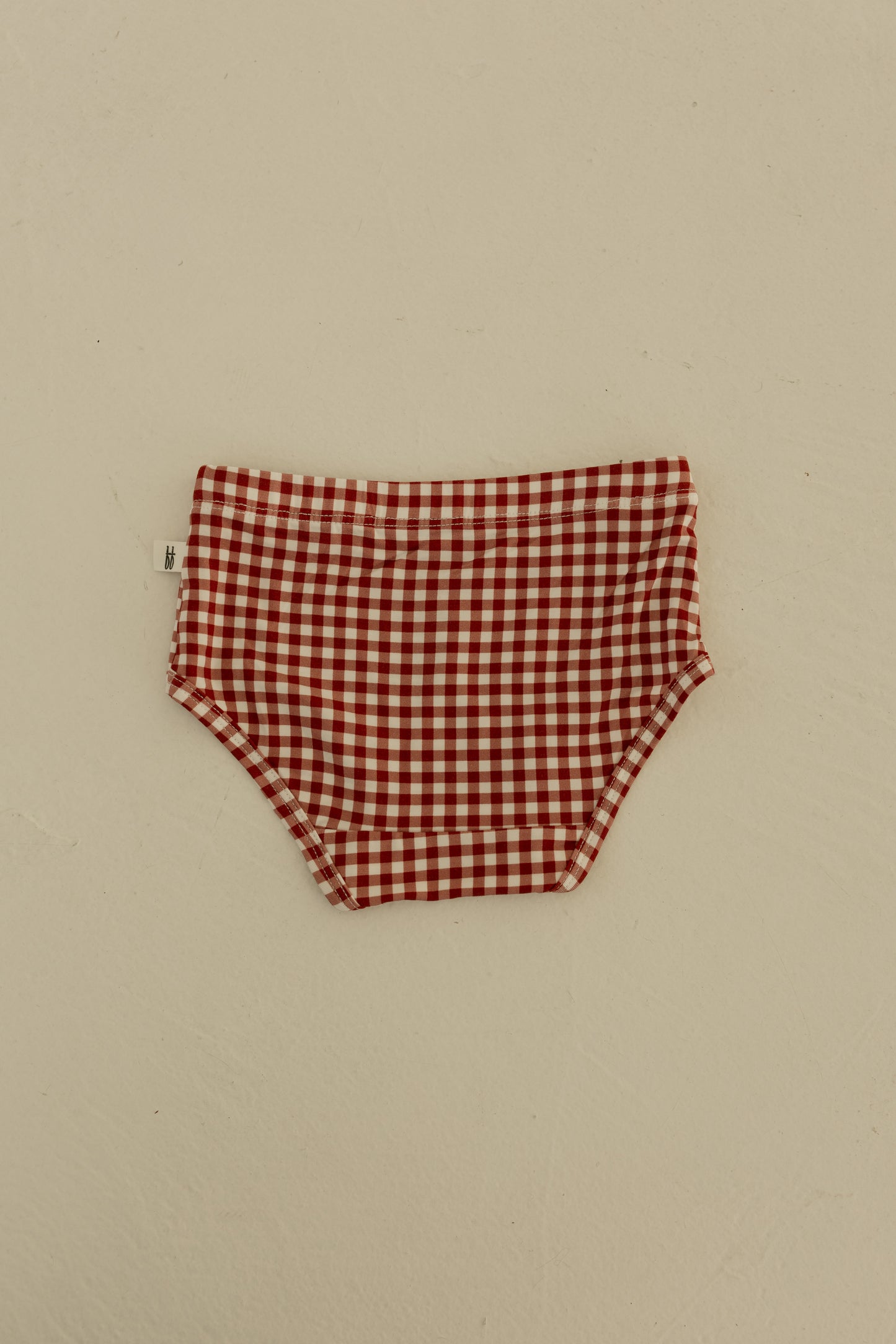 A set of forever french baby Girl's Bamboo Briefs (3 Pack) in Red Gingham, Candy Cane, and Santa Checkerboard patterns is displayed flat on a light surface.