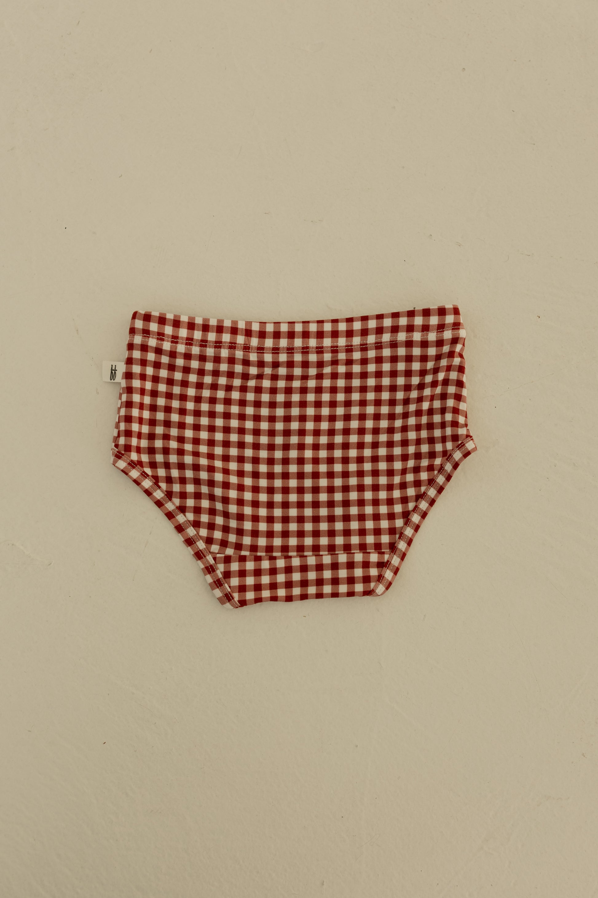 A set of forever french baby Girl's Bamboo Briefs (3 Pack) in Red Gingham, Candy Cane, and Santa Checkerboard patterns is displayed flat on a light surface.