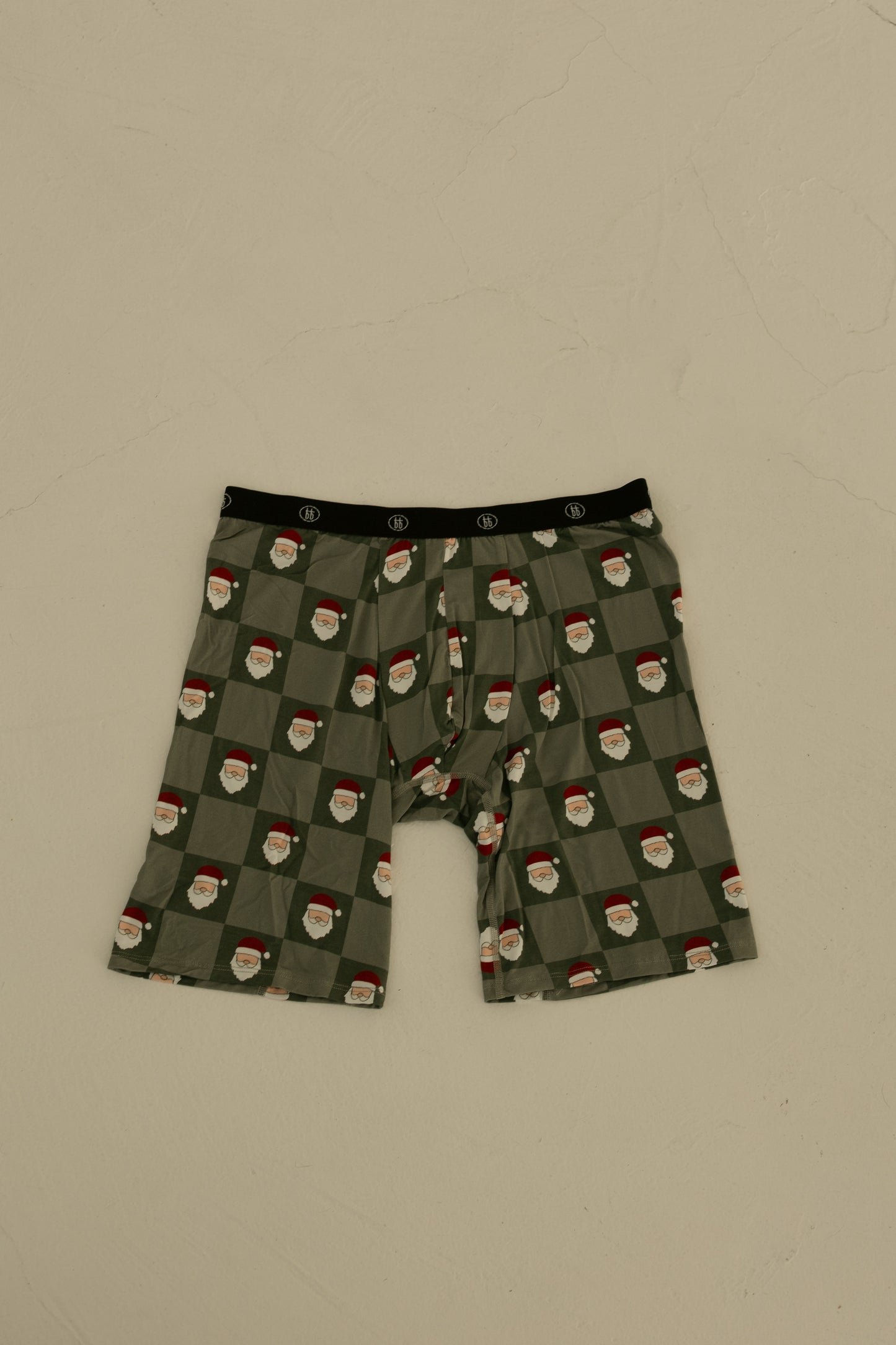 Forever French Baby Men's Bamboo Boxers (3 Pack) in Red Gingham, Candy Cane & Santa Checkerboard feature a festive black waistband and breathable fabric, shown laid flat on a neutral textured surface.