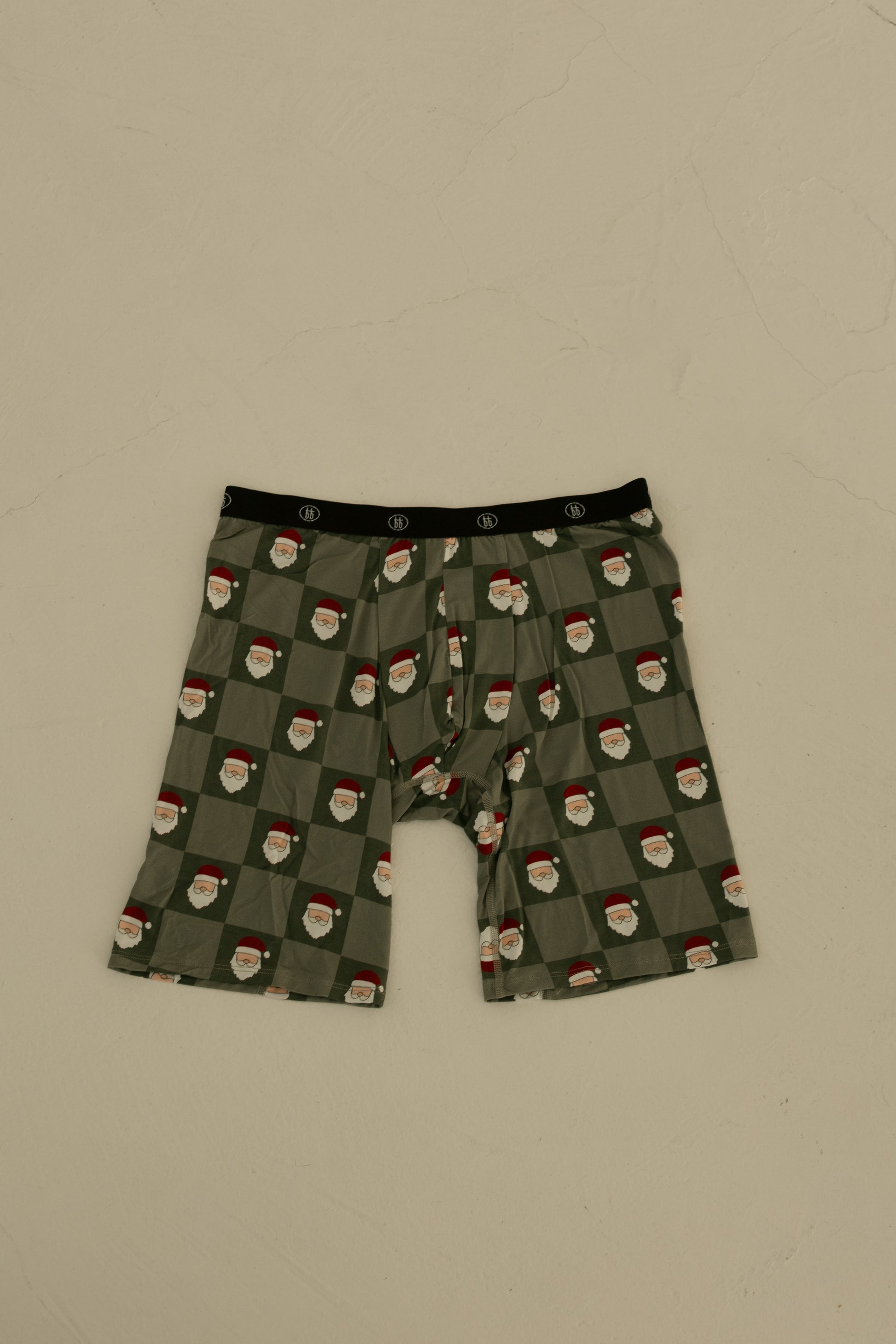 Forever French Baby Men's Bamboo Boxers (3 Pack) in Red Gingham, Candy Cane & Santa Checkerboard feature a festive black waistband and breathable fabric, shown laid flat on a neutral textured surface.