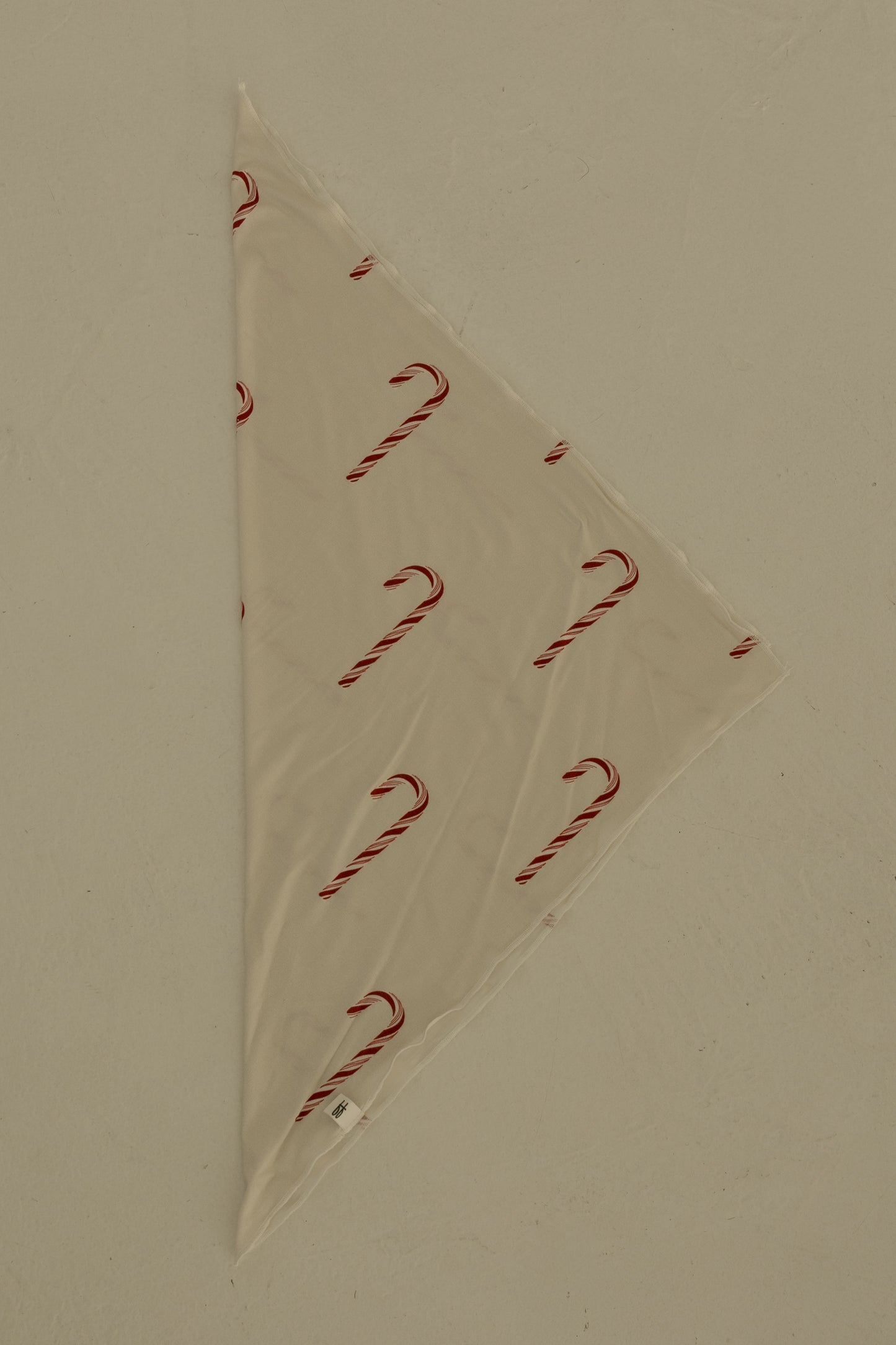 The Bamboo Bandana | Candy Cane by forever french baby is a cream-colored, triangular pet bandana with a festive candy cane print, shown flat on a light surface.