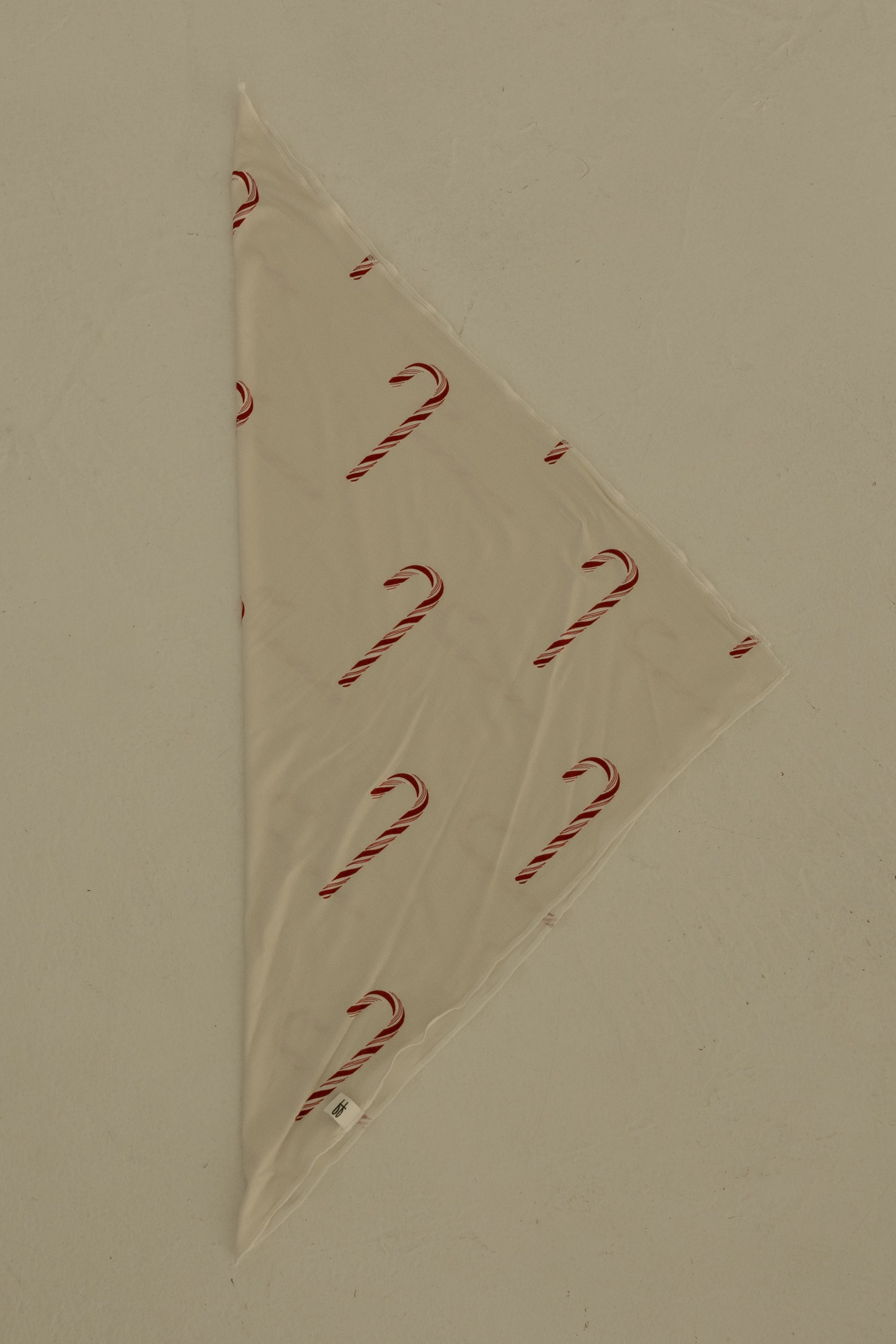 The Bamboo Bandana | Candy Cane by forever french baby is a cream-colored, triangular pet bandana with a festive candy cane print, shown flat on a light surface.