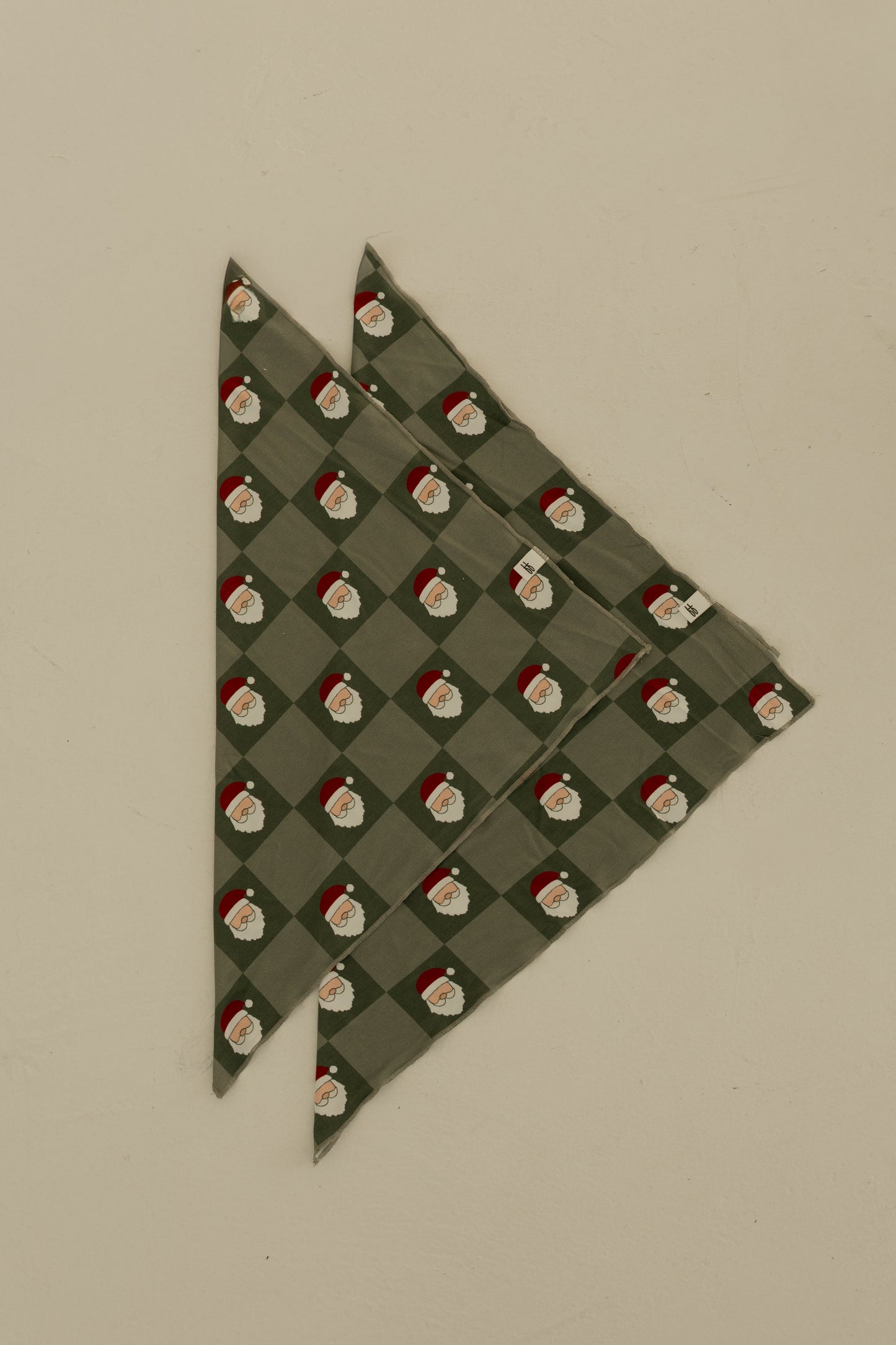 The Bamboo Bandana | Santa Checkerboard by forever french baby, made from soft bamboo viscose, is displayed folded on a plain beige background.
