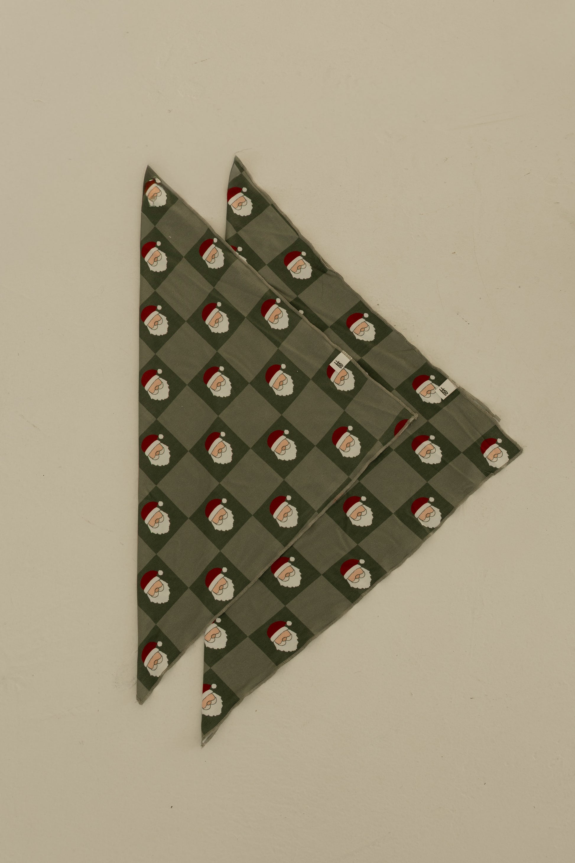 The Bamboo Bandana | Santa Checkerboard by forever french baby, made from soft bamboo viscose, is displayed folded on a plain beige background.