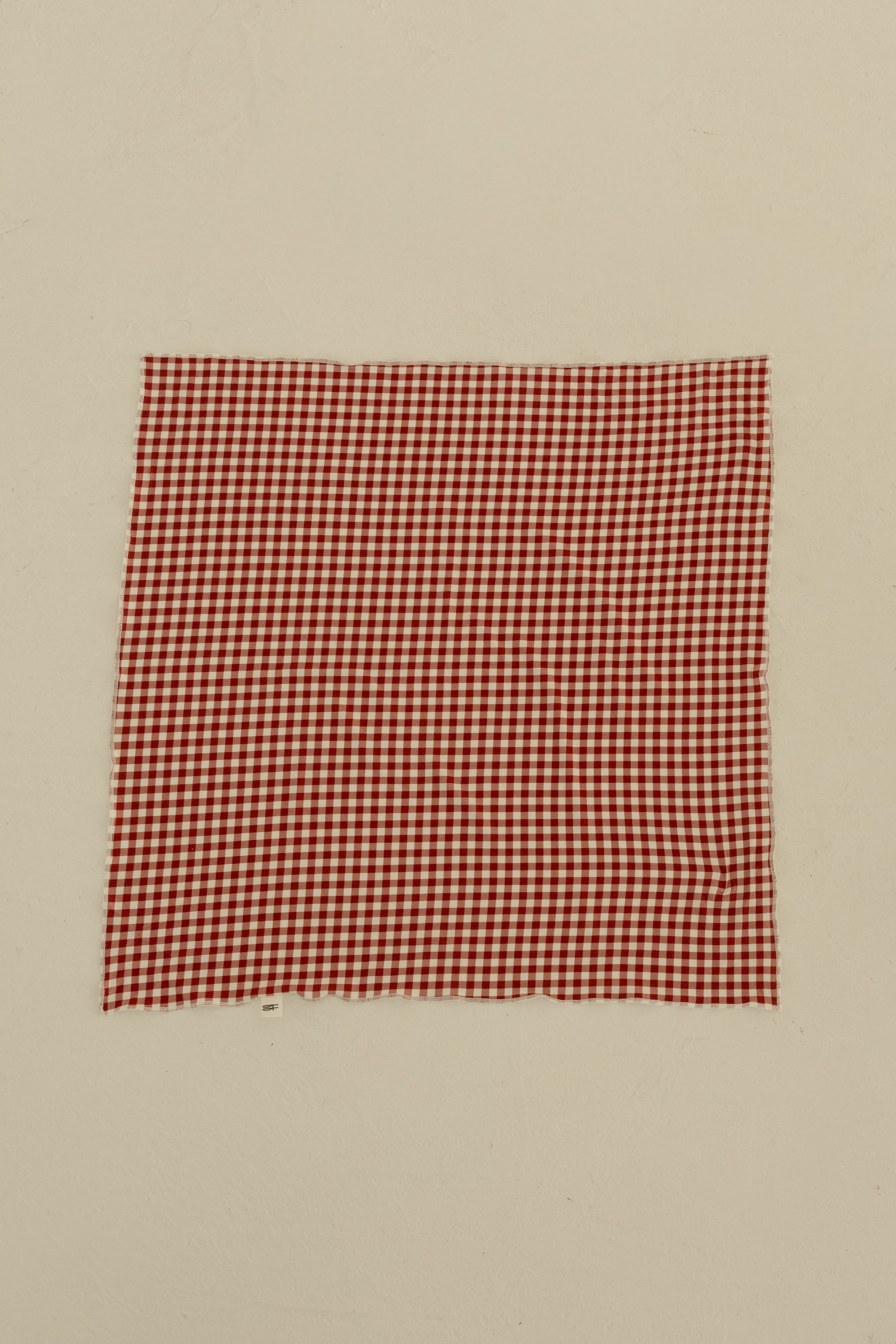 The Bamboo Bandana | Red Gingham by forever french baby, crafted from soft fabric, is displayed flat on a plain, light-colored surface.