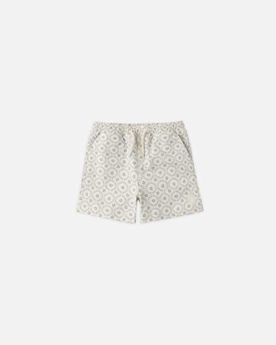 Introducing the “Boardshort | Green Fleur” by Rylee + Cru—these light-hued boardshorts feature an elastic waistband with a drawstring and a repeating geometric floral motif in gentle pastel shades. Crafted from recycled polyester, these stylish shorts are showcased against a plain white background.