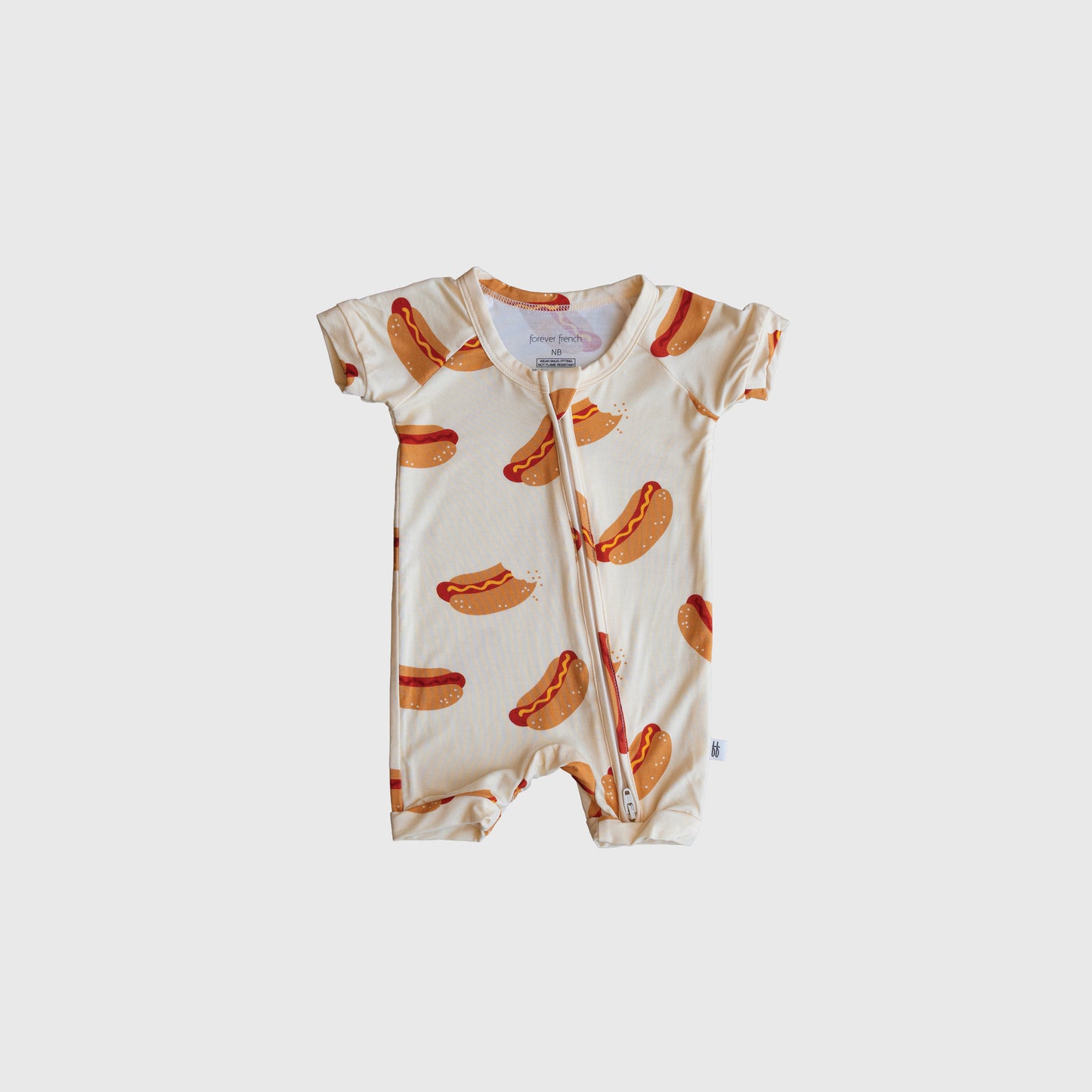 The Shortie Bamboo Zip | Hot Dogs by forever french baby is a hypoallergenic, short-sleeved bamboo romper with a front zipper and playful hot dog print on cream—perfect for your little one’s comfort.