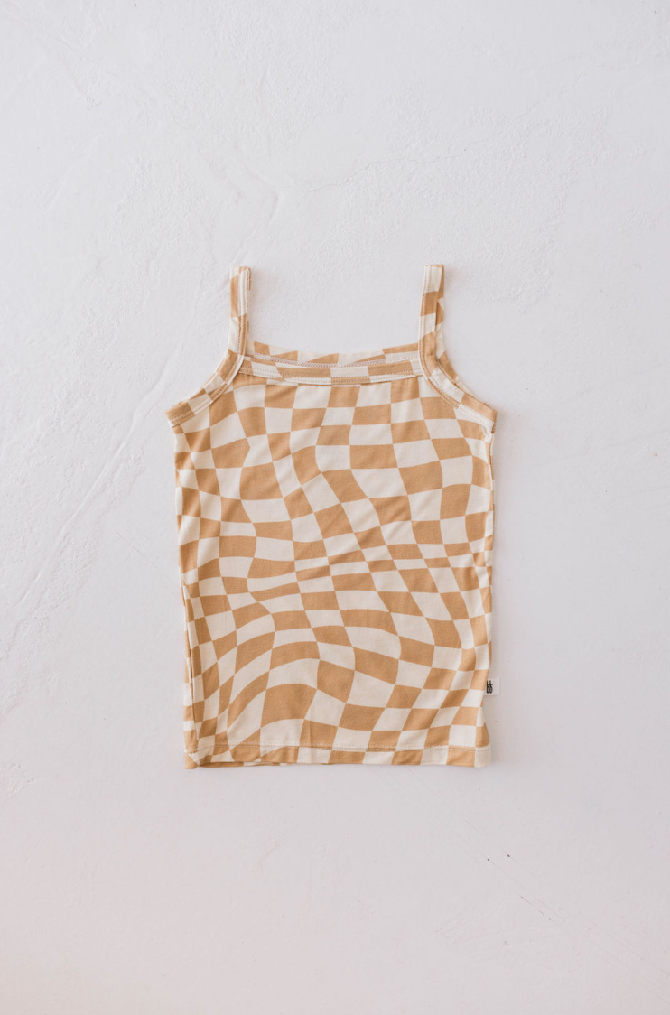 The Basic Bamboo Tank | Gold Coast from forever french baby, featuring a sleeveless design with a beige and white checkered pattern in a wavy print, is laid flat on a white textured surface. Renowned for its hypo-allergenic properties, the distorted checkered print creates an optical illusion effect.